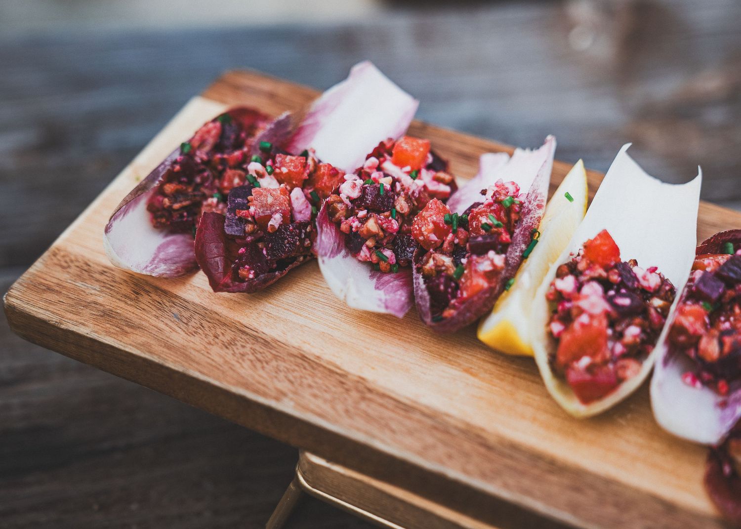 Appetizing tuna tartare served in crispy taco shells on a wooden serving board with garnishes.