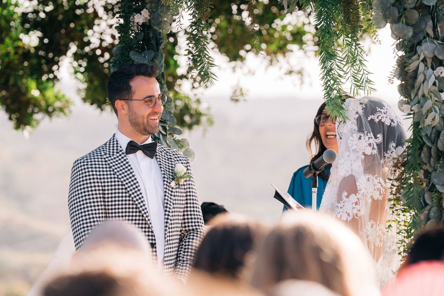 An outdoor wedding ceremony with a couple at the altar surrounded by greenery and guests.