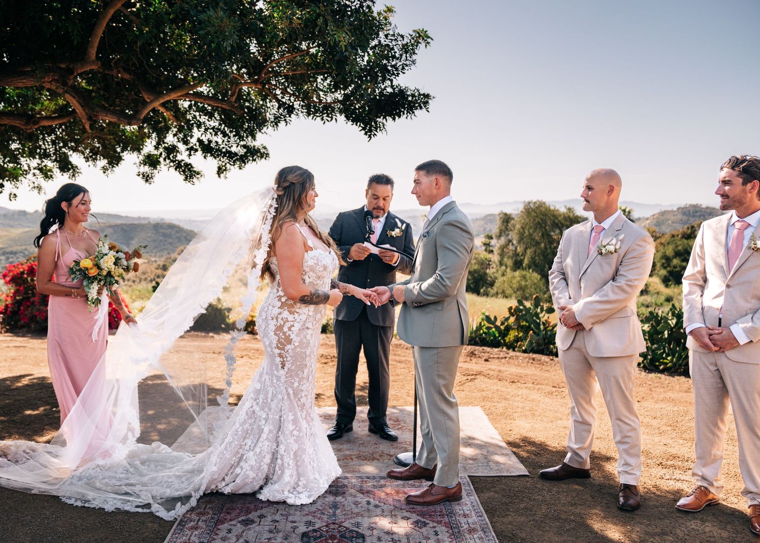 Wedding party gathered on a hilltop during golden hour celebration with scenic mountain backdrop.