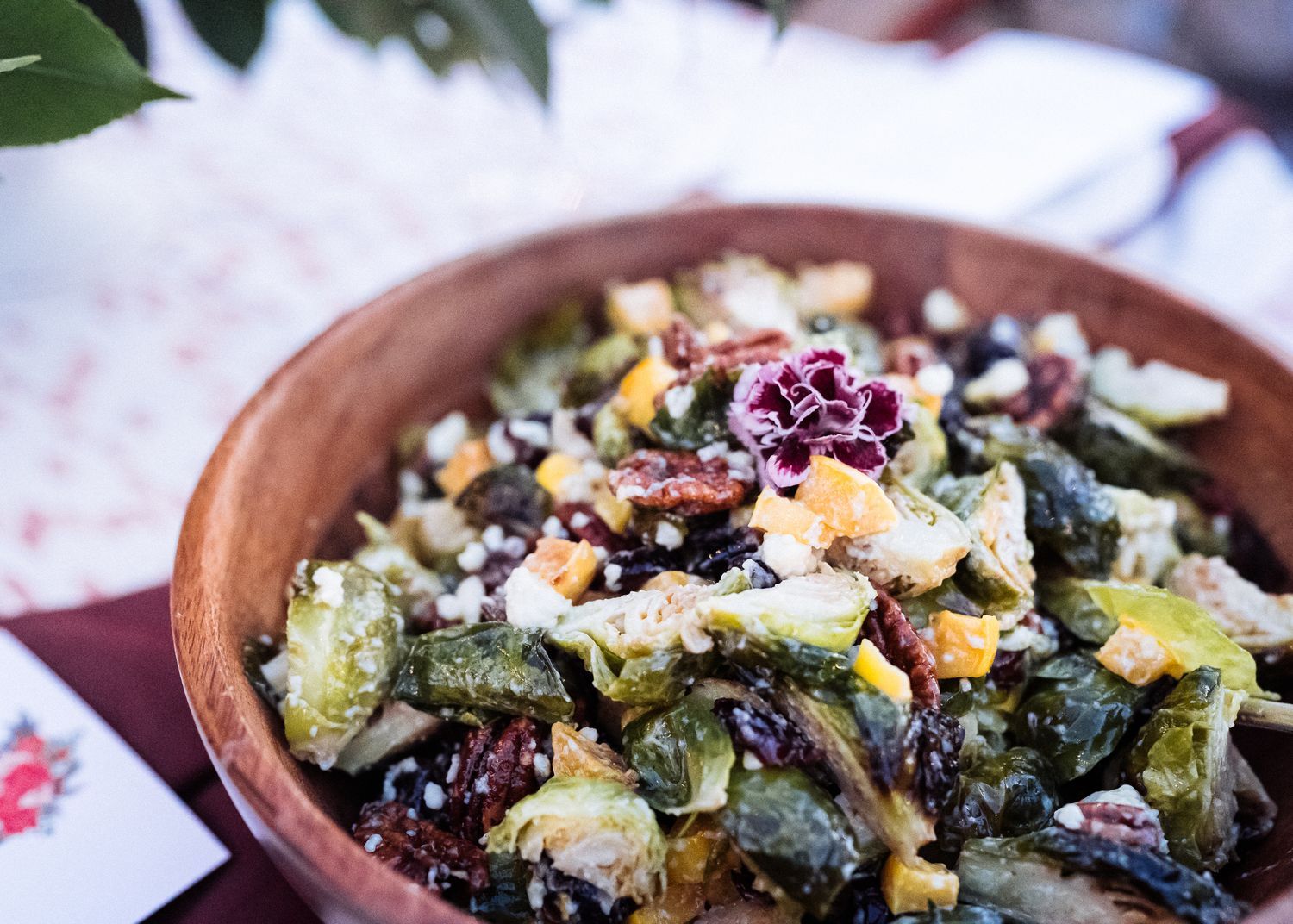 Close up view of a rustic kale salad with dried fruit and nuts in an earthenware bowl.