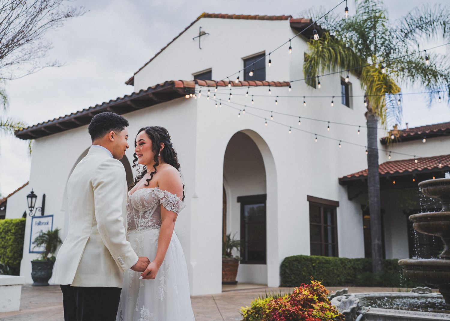 An elegant Spanish Colonial style home with white stucco walls and terracotta roof tiles at sunset.