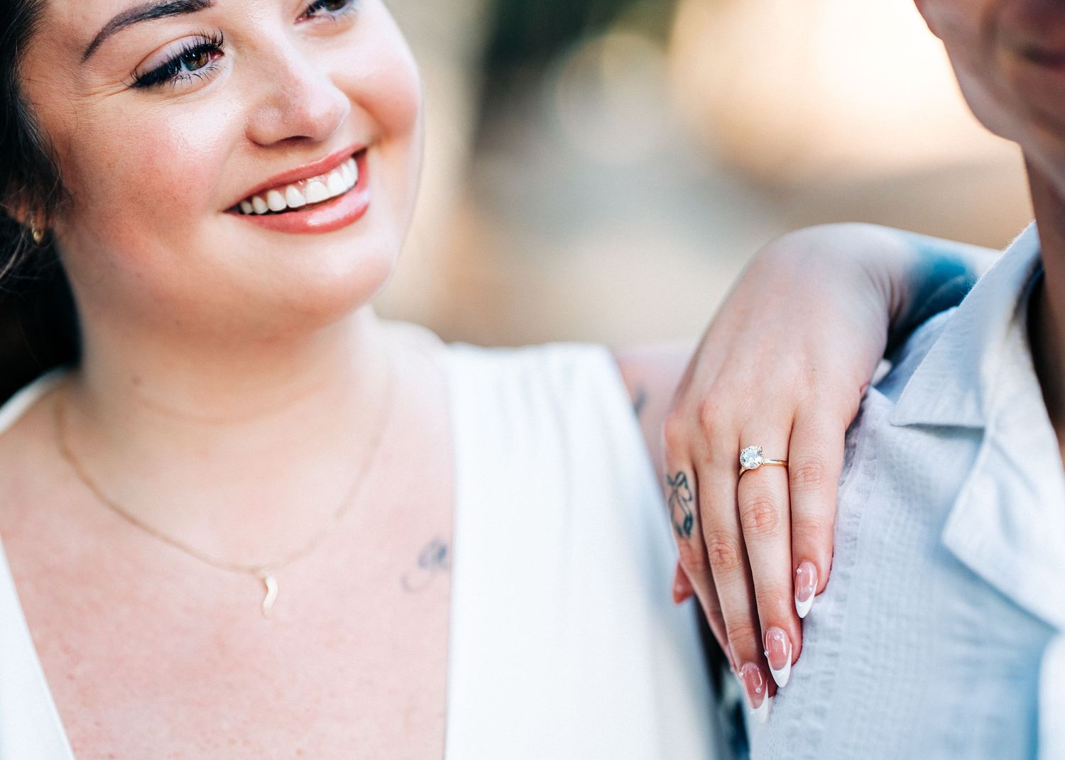 Close up photo showing a bright smile and engagement ring detail during a romantic moment.