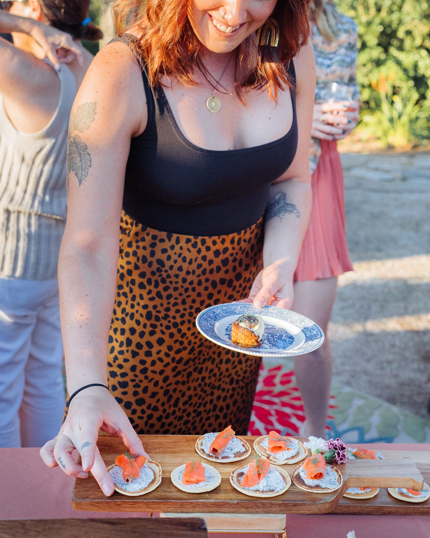 Party appetizers featuring smoked salmon blinis being served at an outdoor gathering.