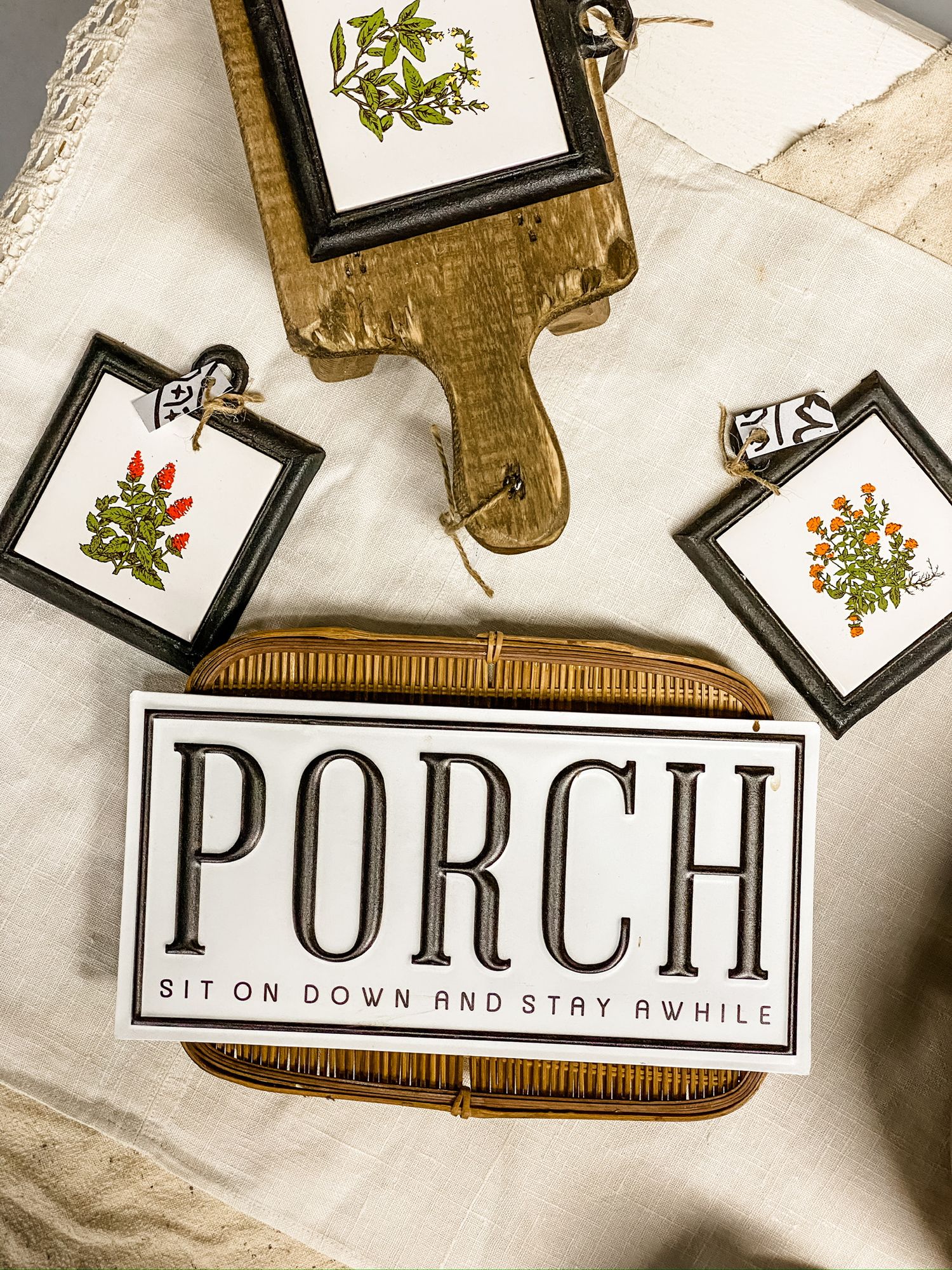 Rustic wooden sign with 'PORCH' text surrounded by small framed botanical prints.