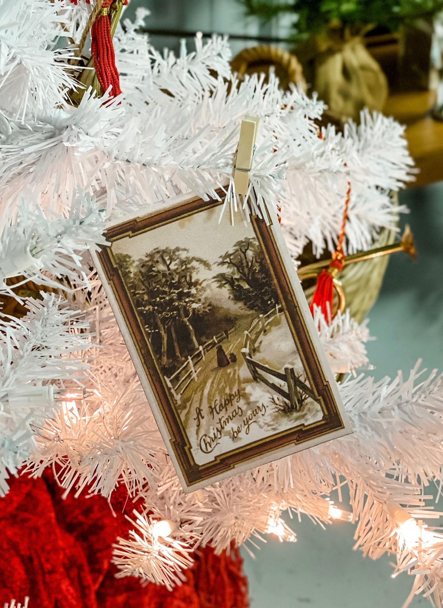 Vintage Christmas card clipped to white tinsel tree with red accents.
