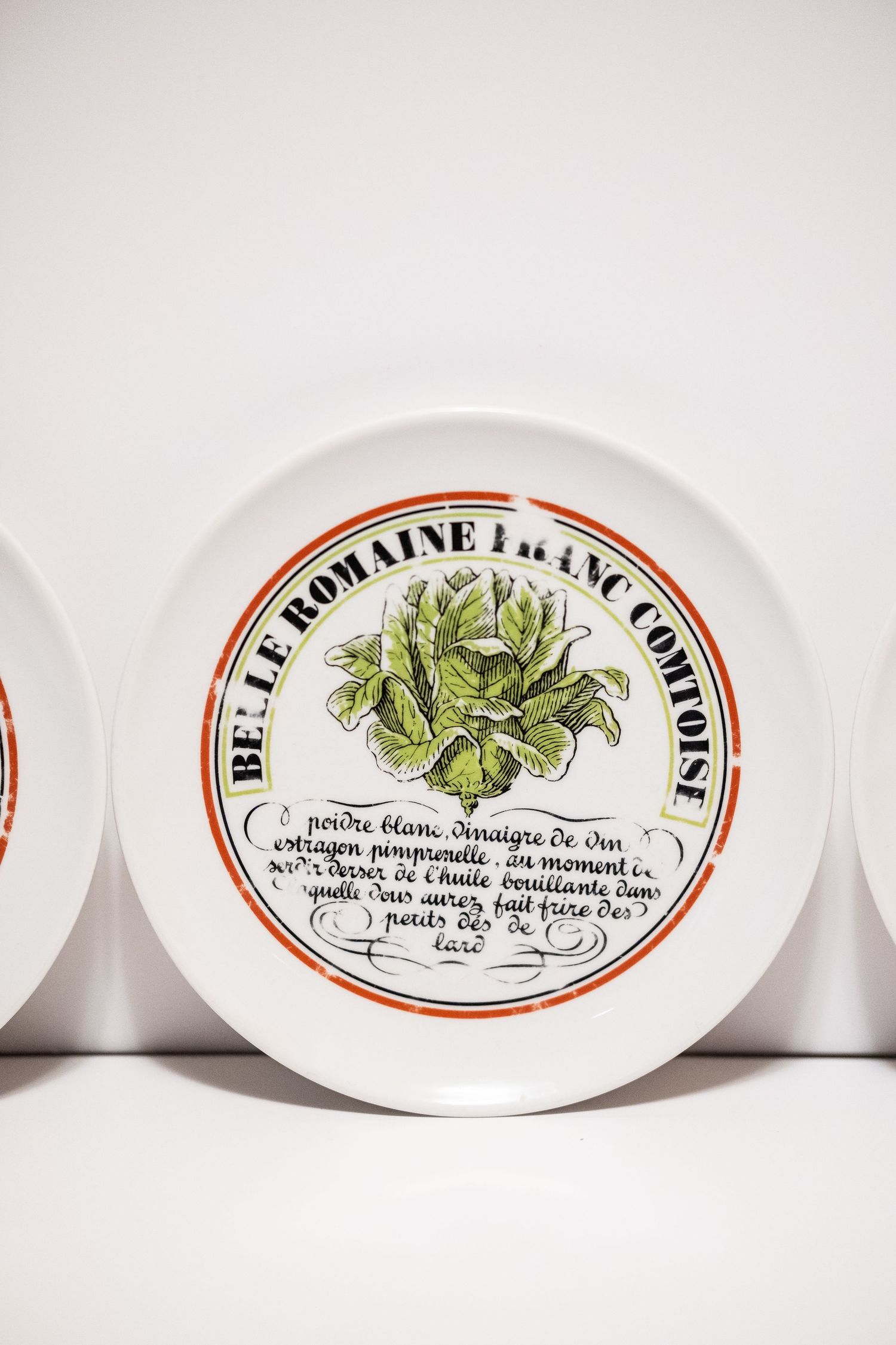 Vintage French ceramic plate featuring Belle Romaine Franc Comtoise lettuce illustration with decorative text and orange border.