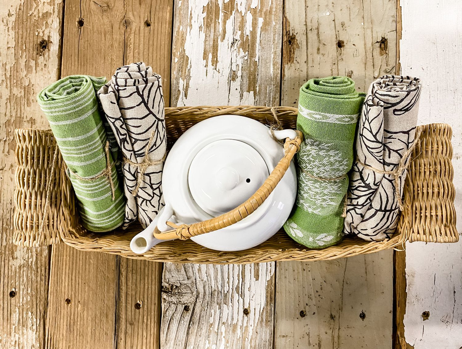 Decorative display of rolled green and white towels with ceramic plate on wooden surface.