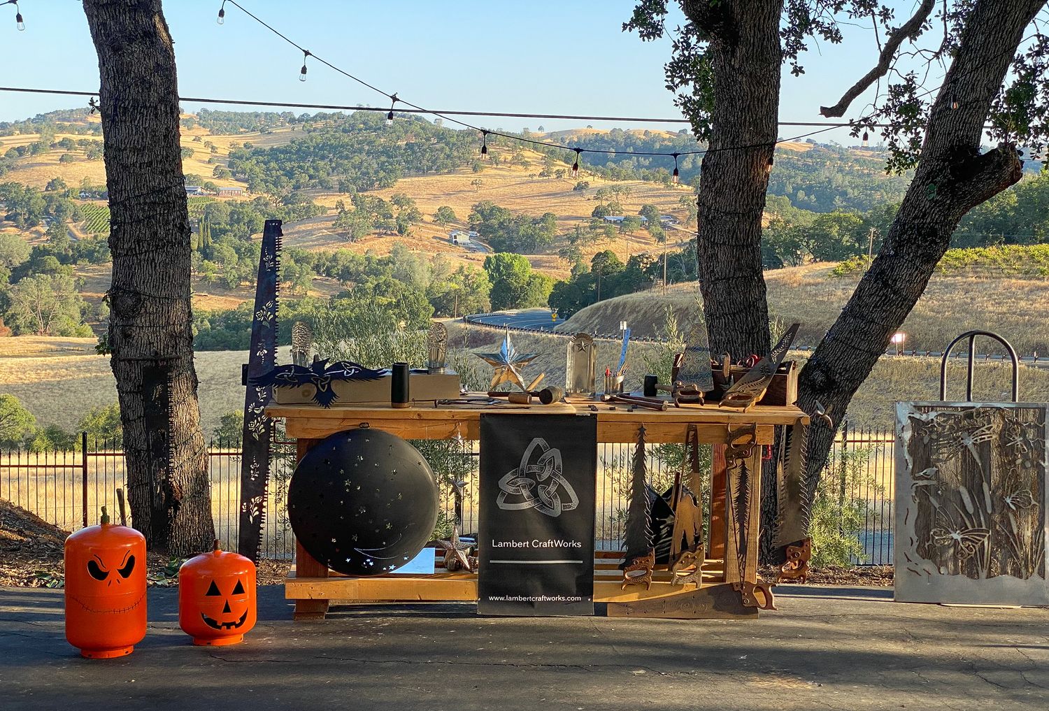 Outdoor bar setup with Halloween pumpkins against a scenic hillside backdrop at sunset.