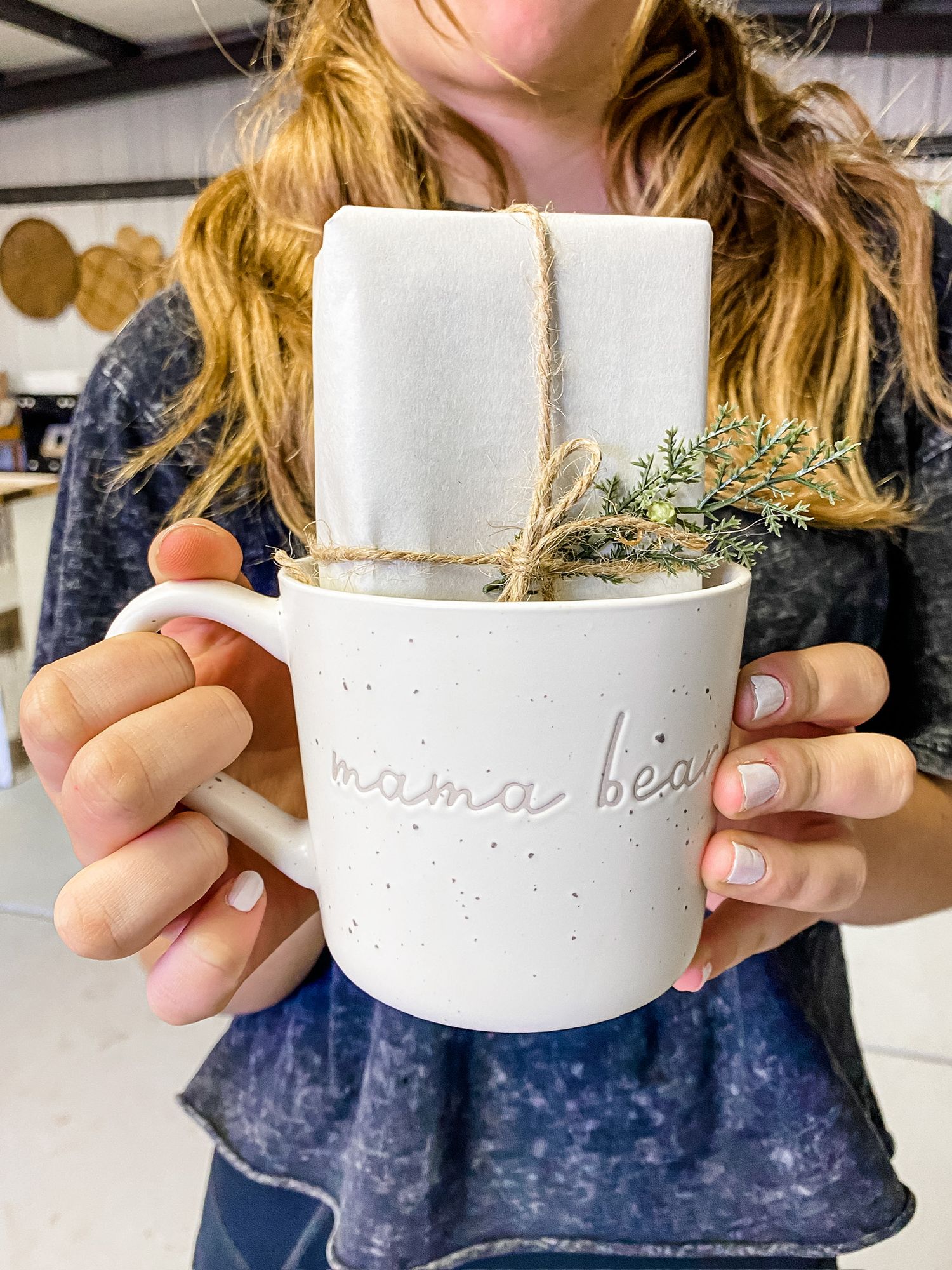 White ceramic mug decorated with twine and sprigs of greenery.
