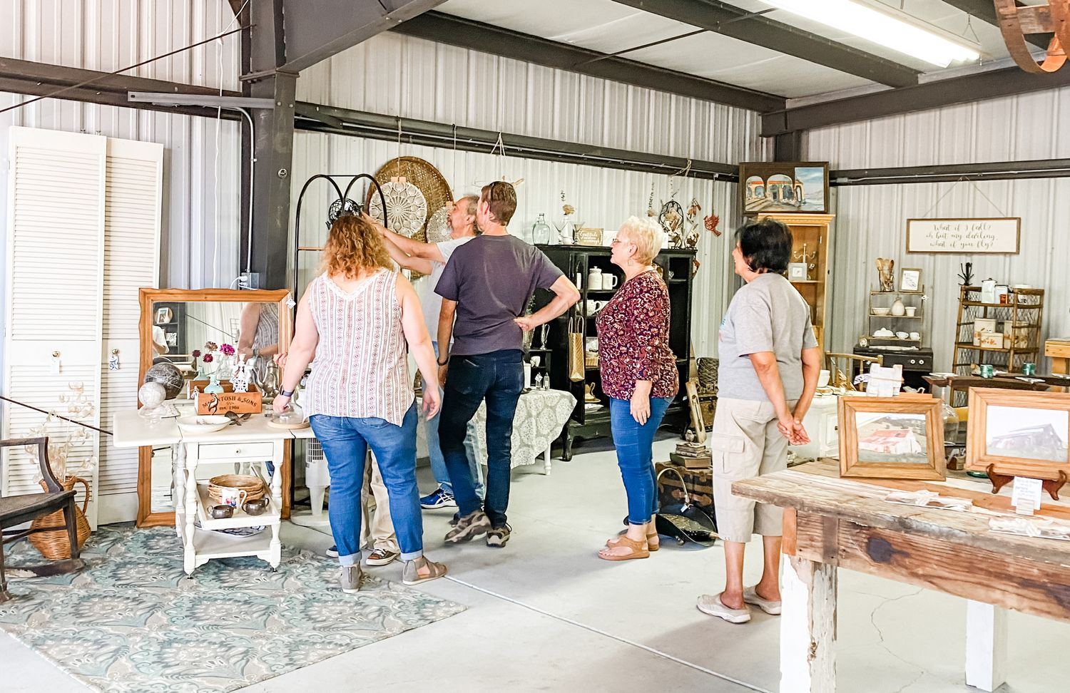 Shoppers browsing vintage items in a well-lit indoor antique market.