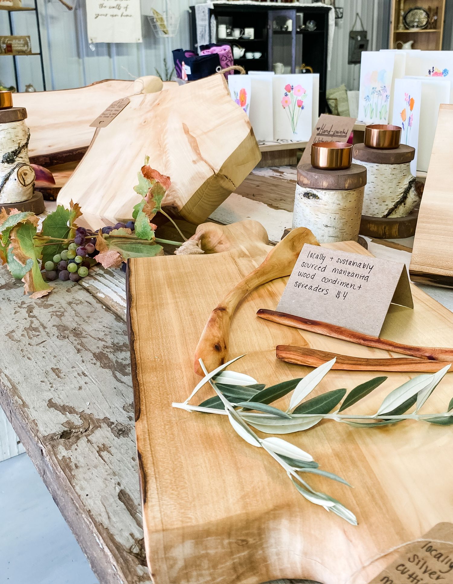 Rustic table setting with olive branches, fabric, and wooden accessories in neutral tones.
