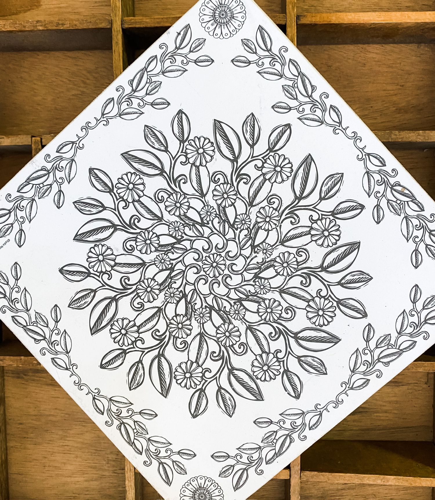 Black and white floral mandala design drawing with intricate leaf patterns.