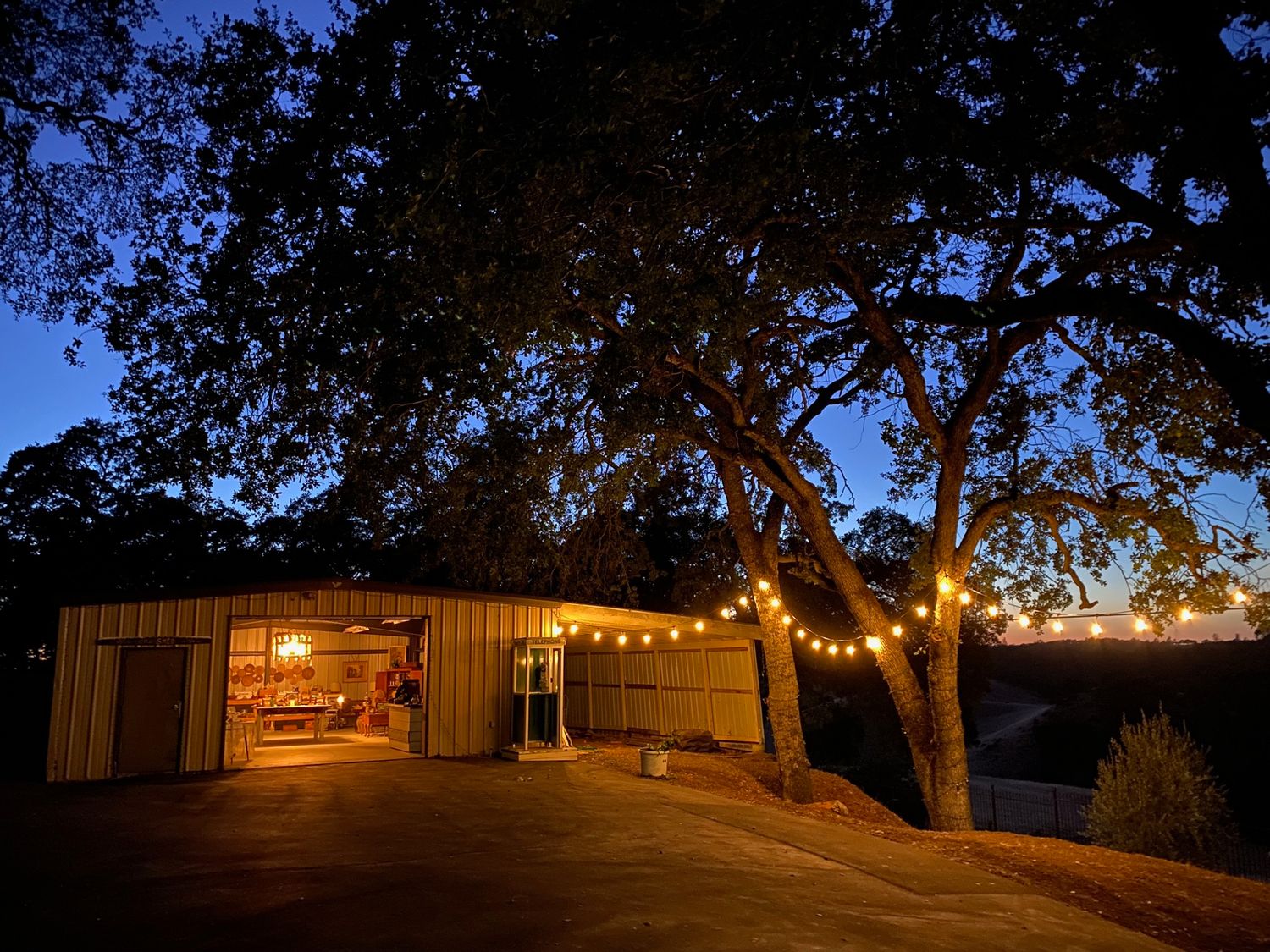 Rustic barn venue illuminated by string lights at dusk with a warm glowing entrance.