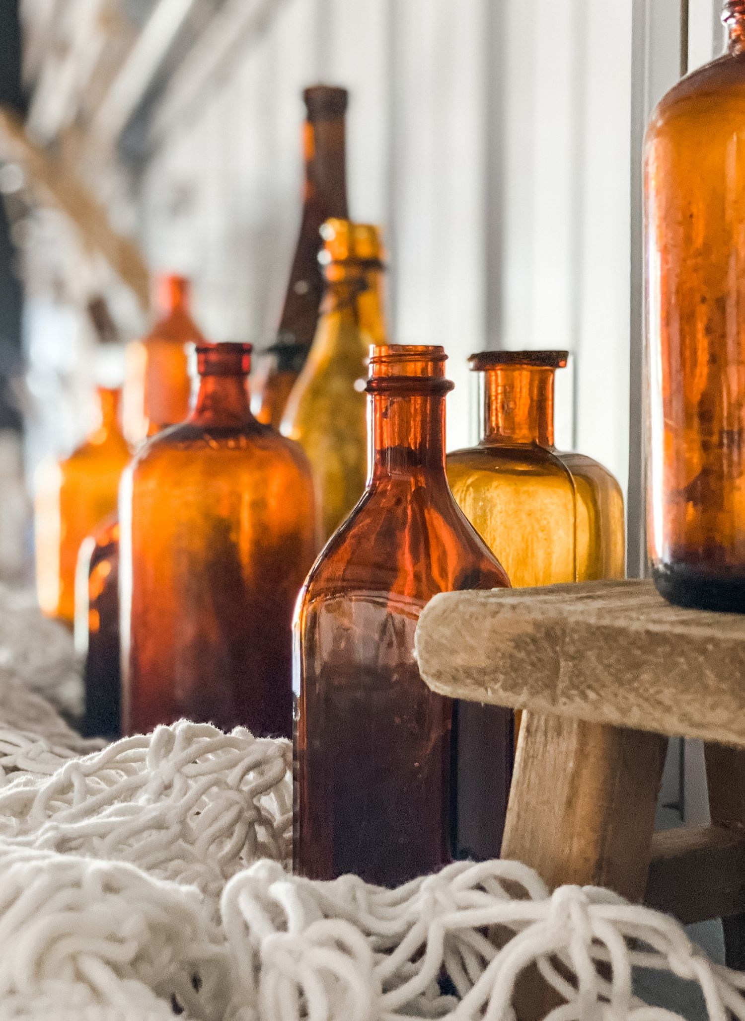 Vintage amber glass bottles arranged in a row with rustic rope and natural lighting.
