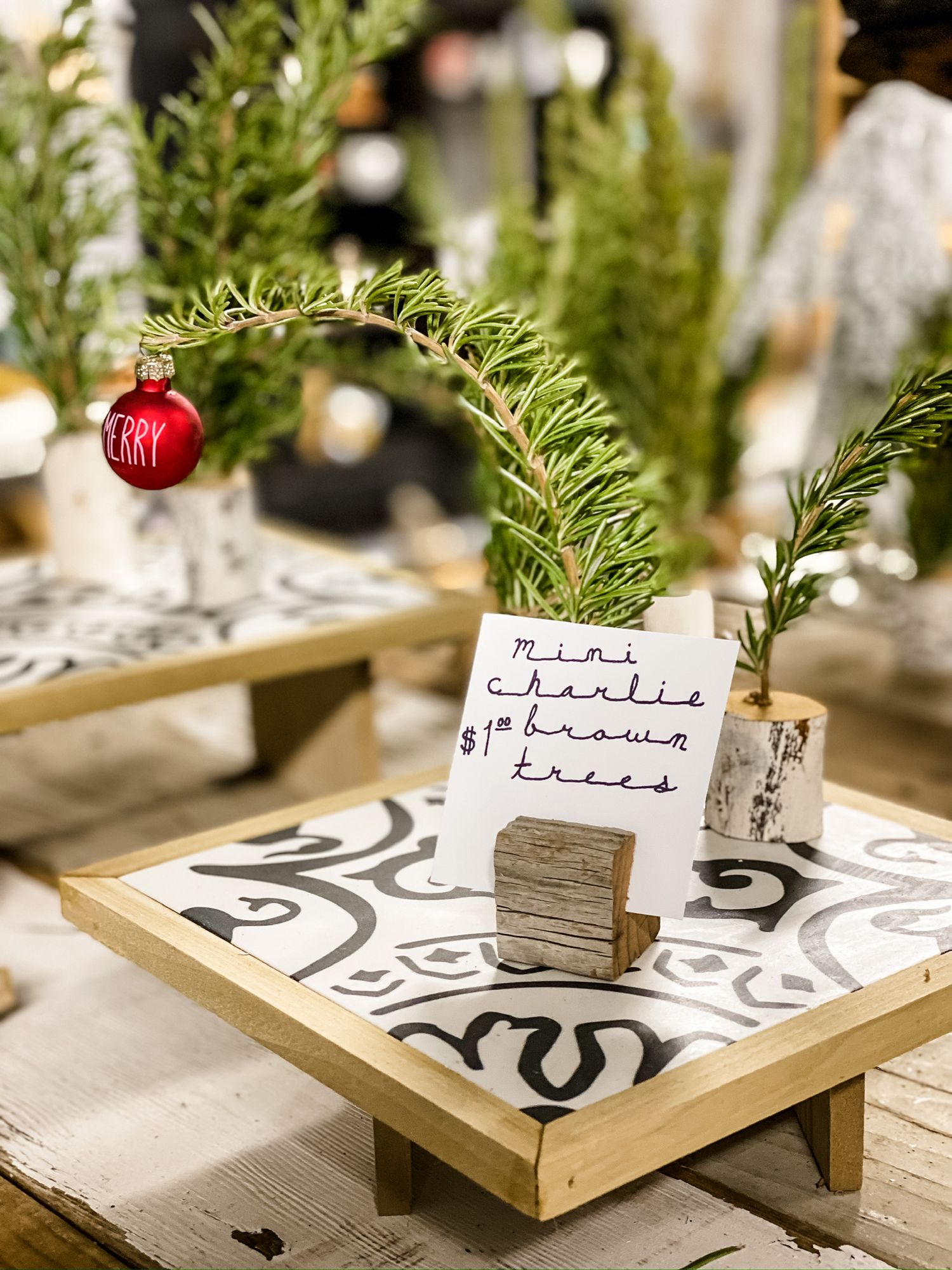 Holiday decorated tray with small red ornament and greenery on patterned tile surface.