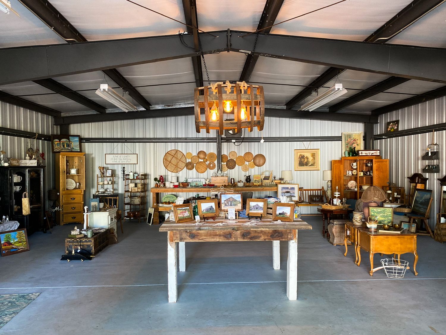 Spacious vintage retail shop interior with wooden displays, hanging lights and rustic decor.