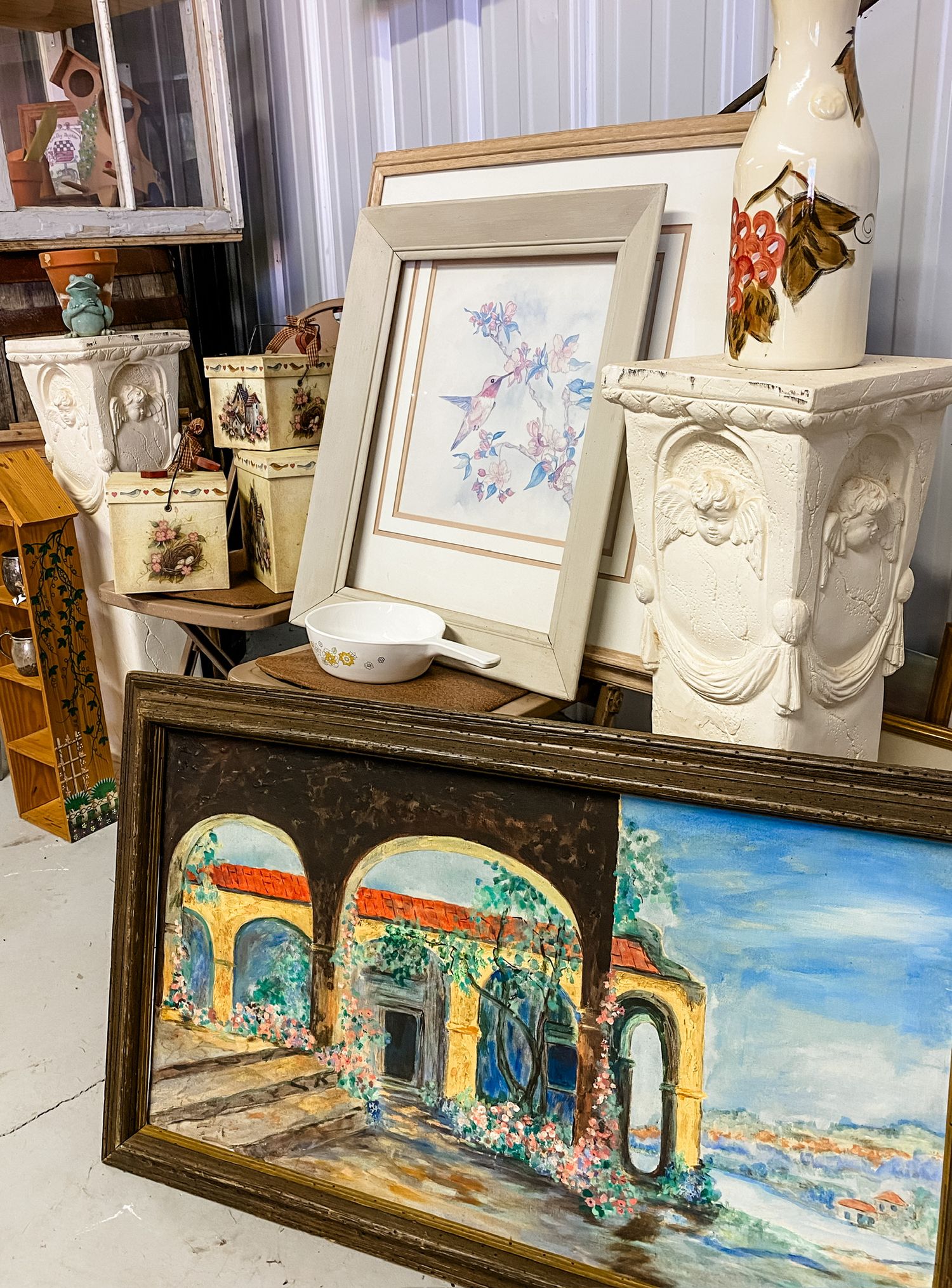 Collection of framed artwork and decorative items displayed on a vintage surface.