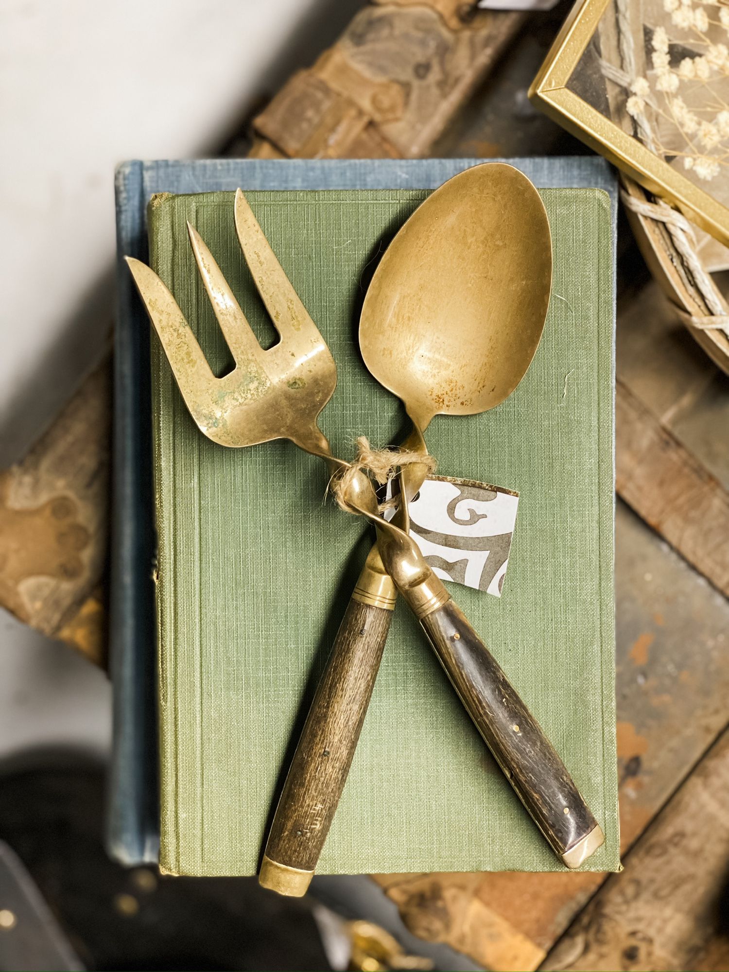 Vintage gold-toned serving utensils displayed on a green book cover.