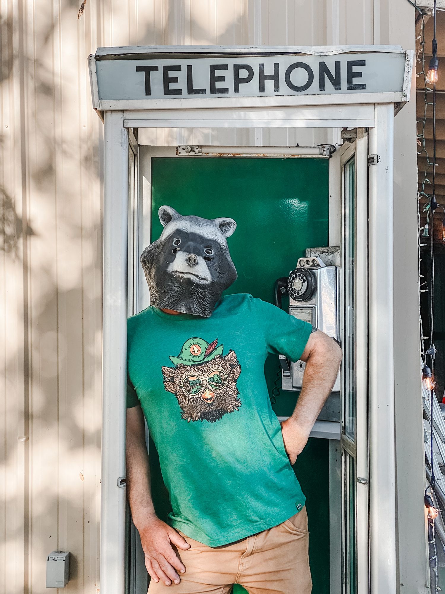 Green telephone booth with decorative raccoon mascot display.