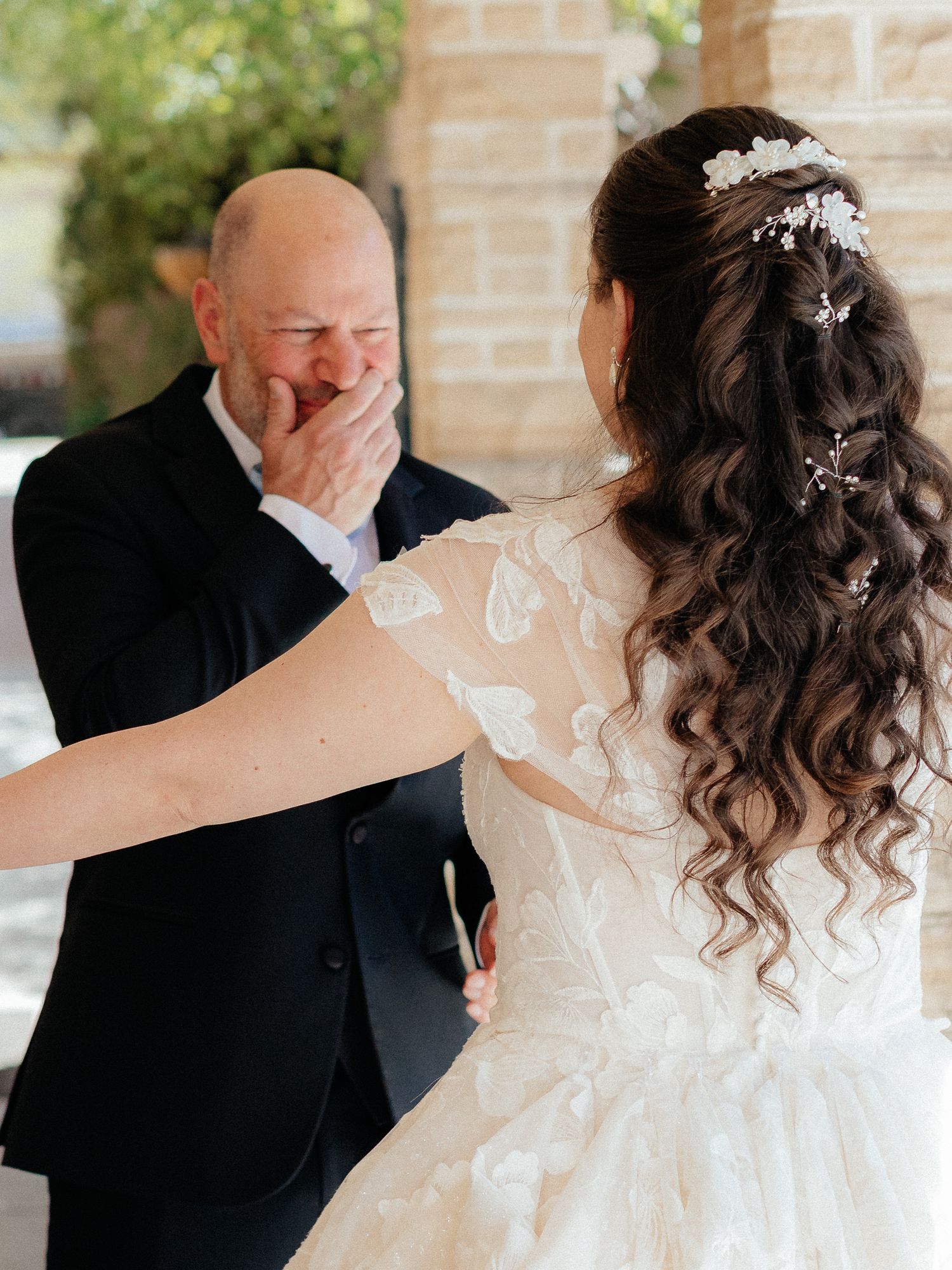 Emotional father covering his mouth in tears seeing his daughter in her wedding gown during a first look moment.