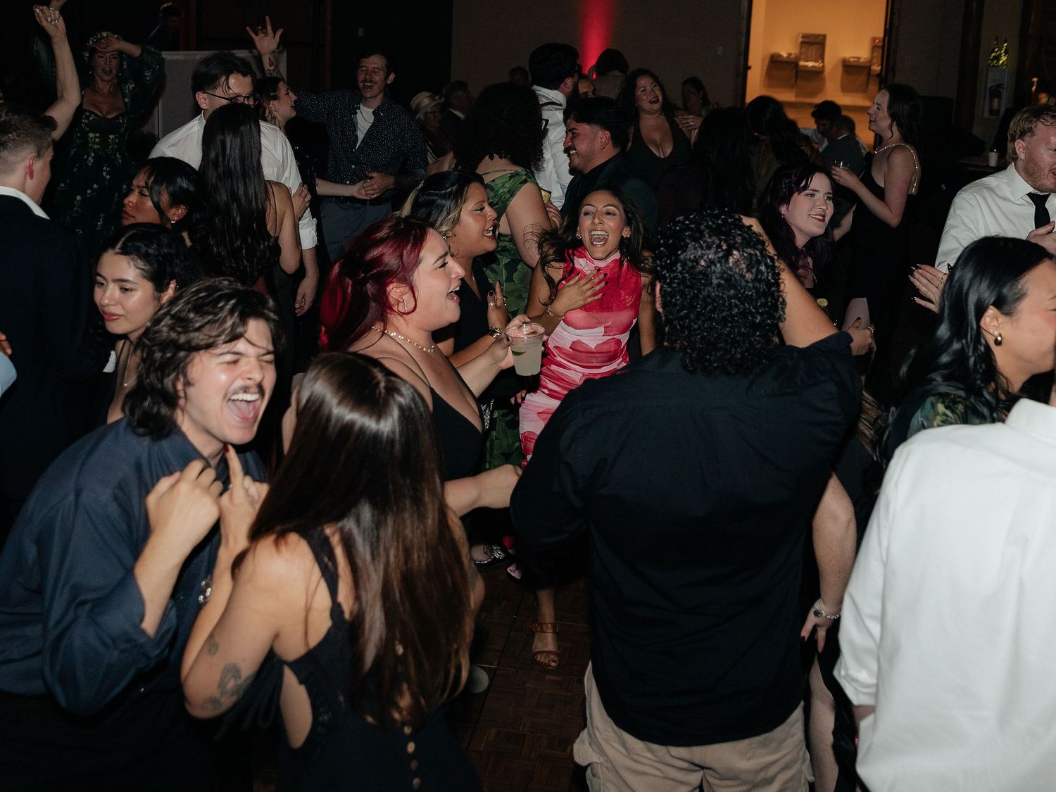 Crowd of young adults dancing and celebrating together at a formal party or prom event.