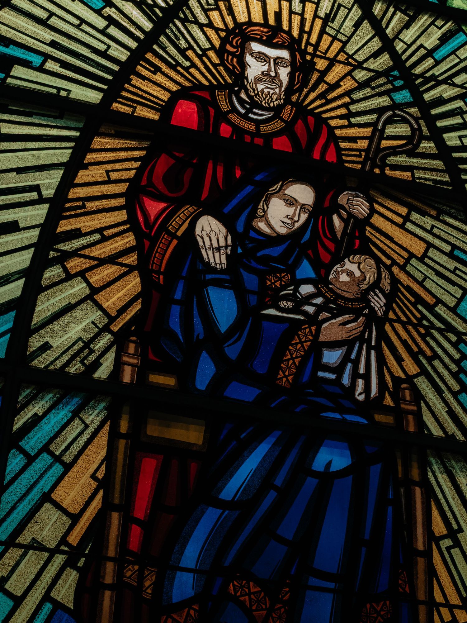 Beautiful stained glass window depicting Holy Family with Joseph, Mary, and baby Jesus in church.