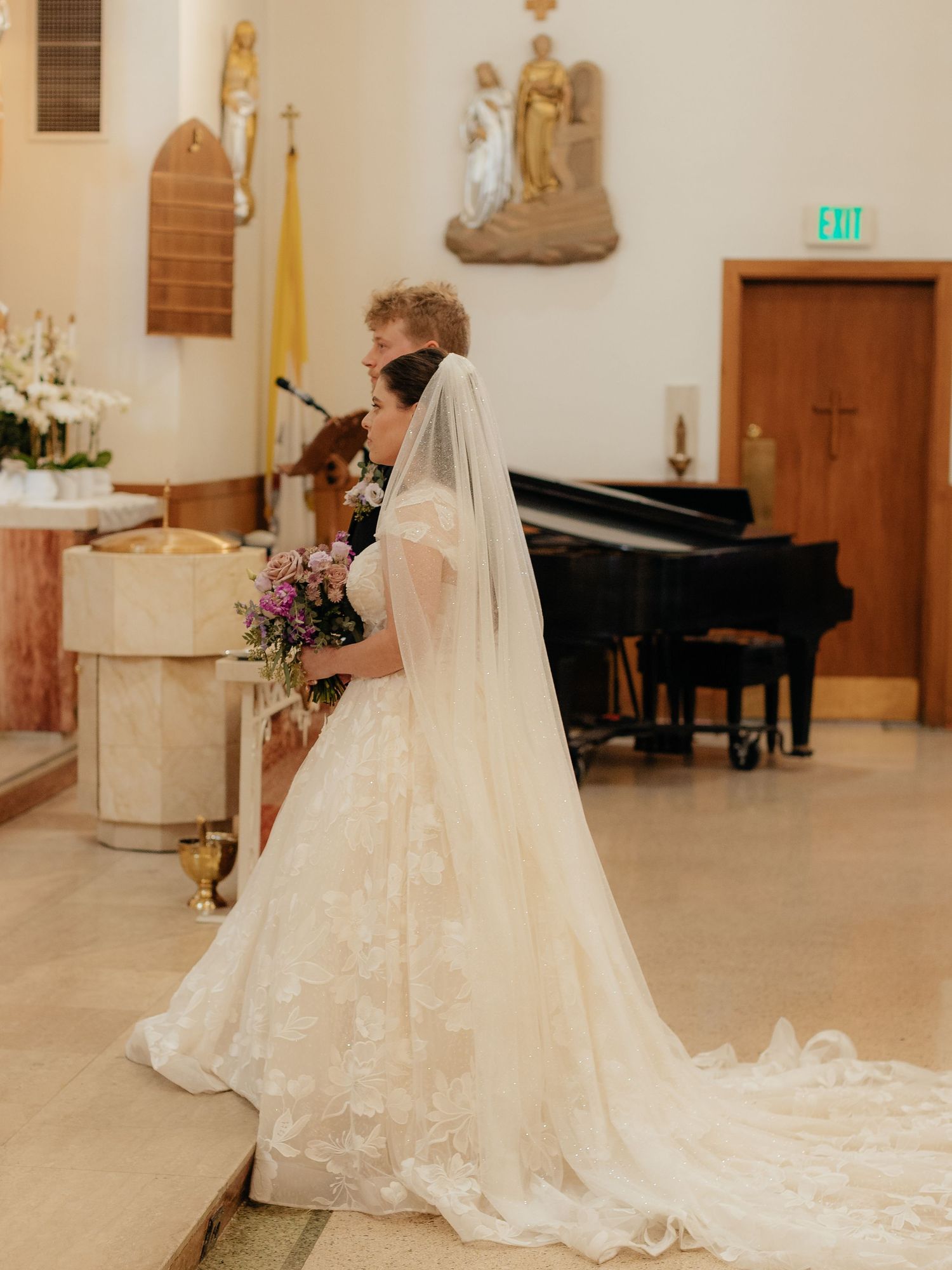 Bride and groom share an intimate moment at the altar during a church wedding ceremony, bride in lace gown with veil.