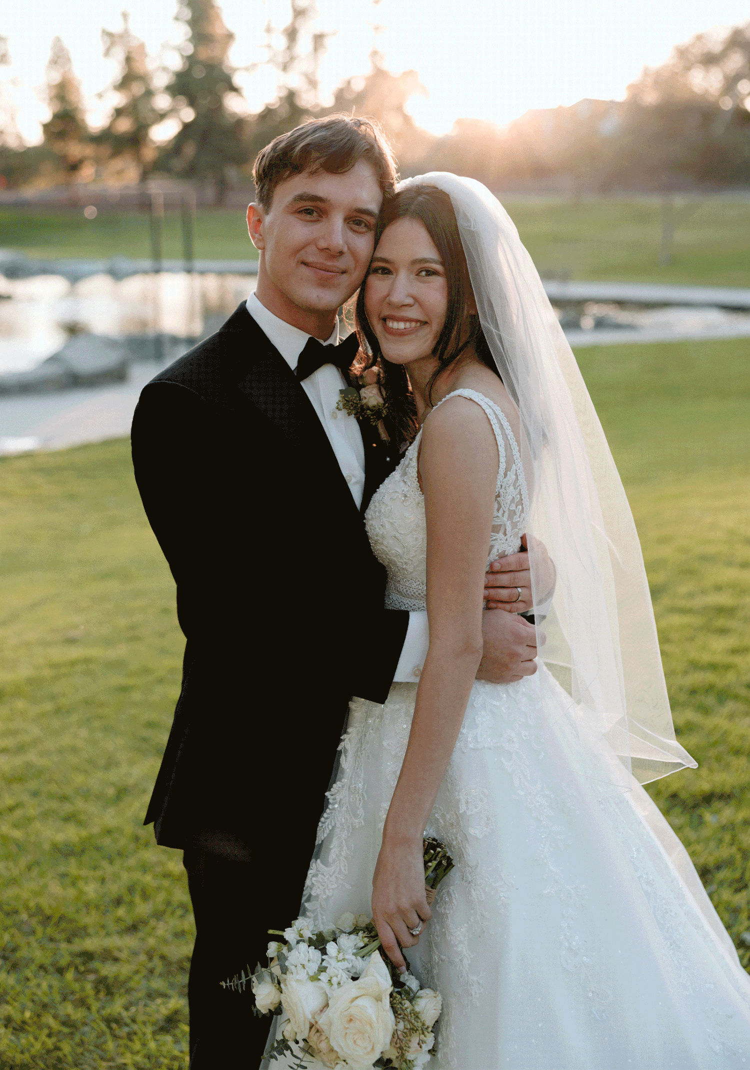 Romantic sunset wedding portraits show a couple embracing on a grassy lawn in golden evening light.