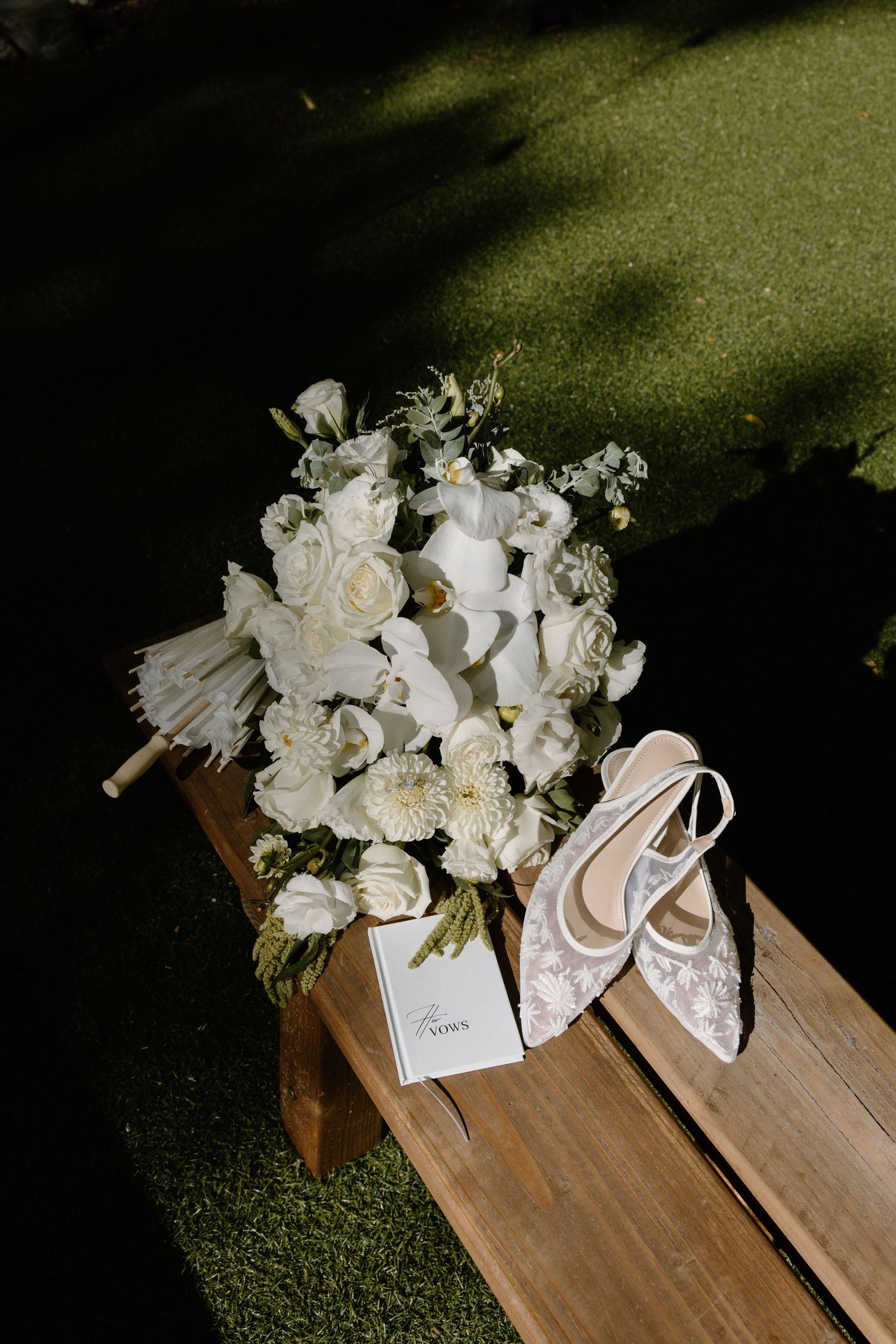 White floral bouquets arranged on wooden benches create an elegant wedding ceremony aisle decoration.