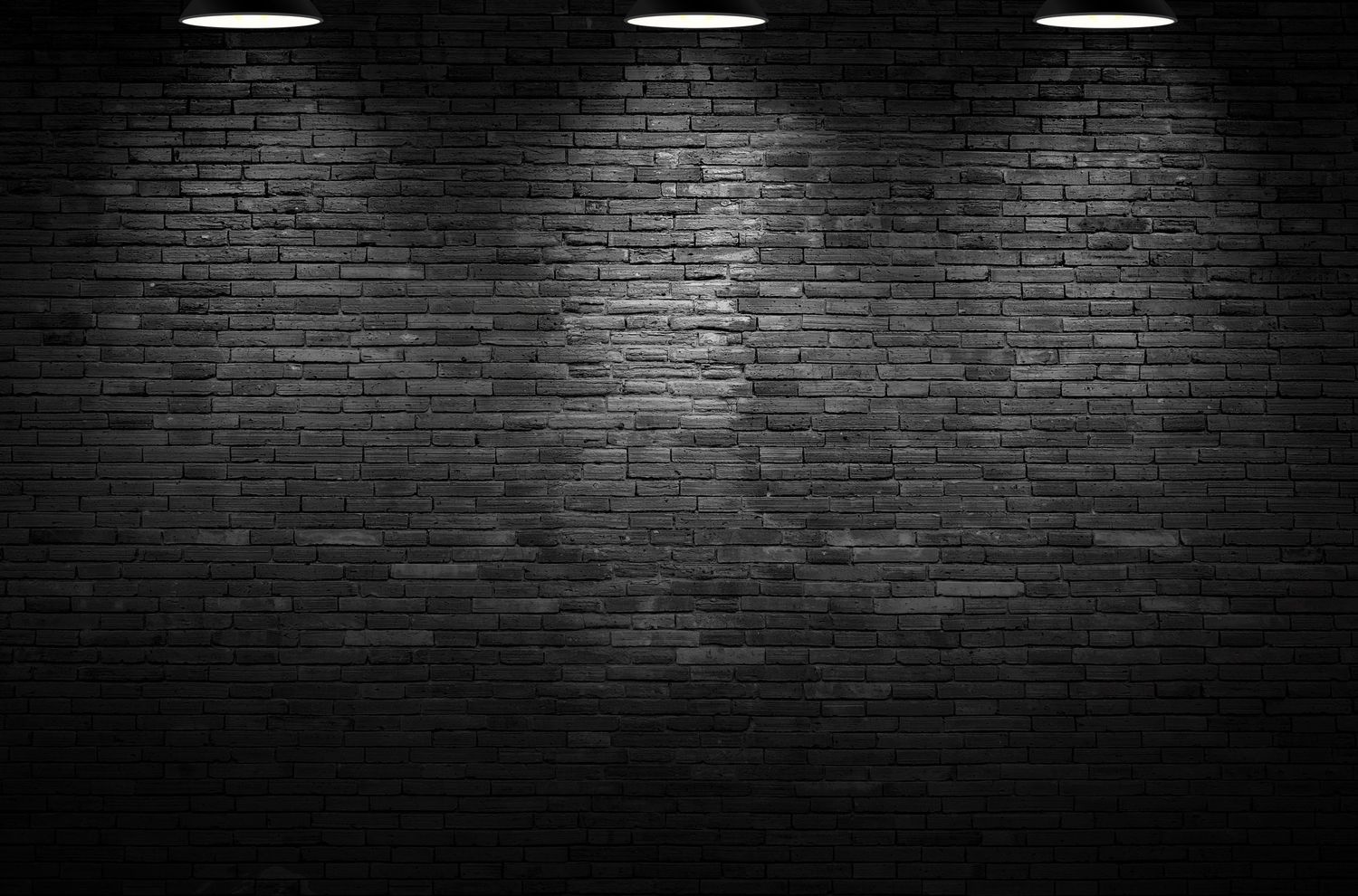 Dark brick wall with dramatic overhead spotlight lighting creating moody shadows.
