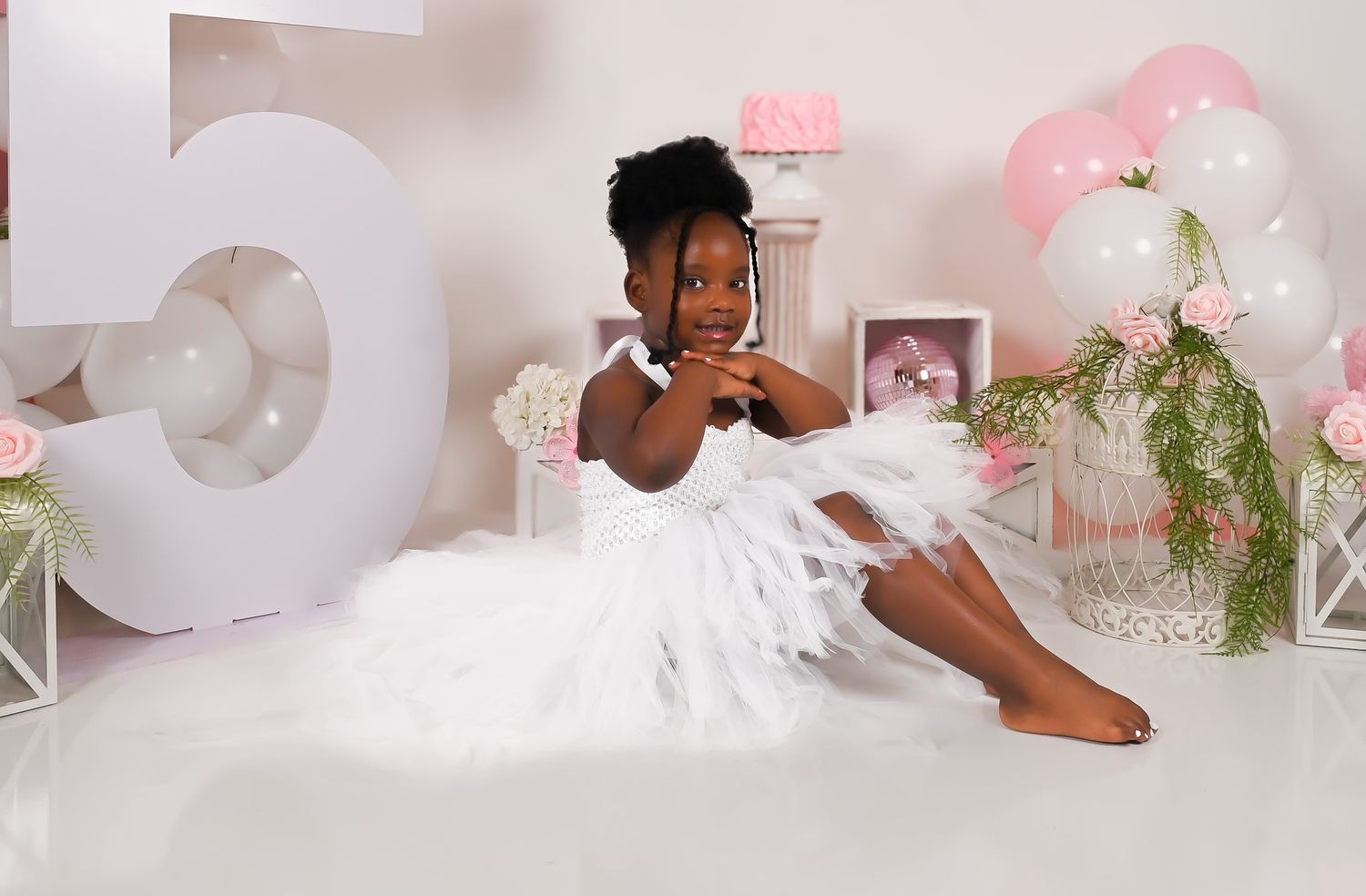 Professional photo studio setup with pink and white balloons and floral decorations.