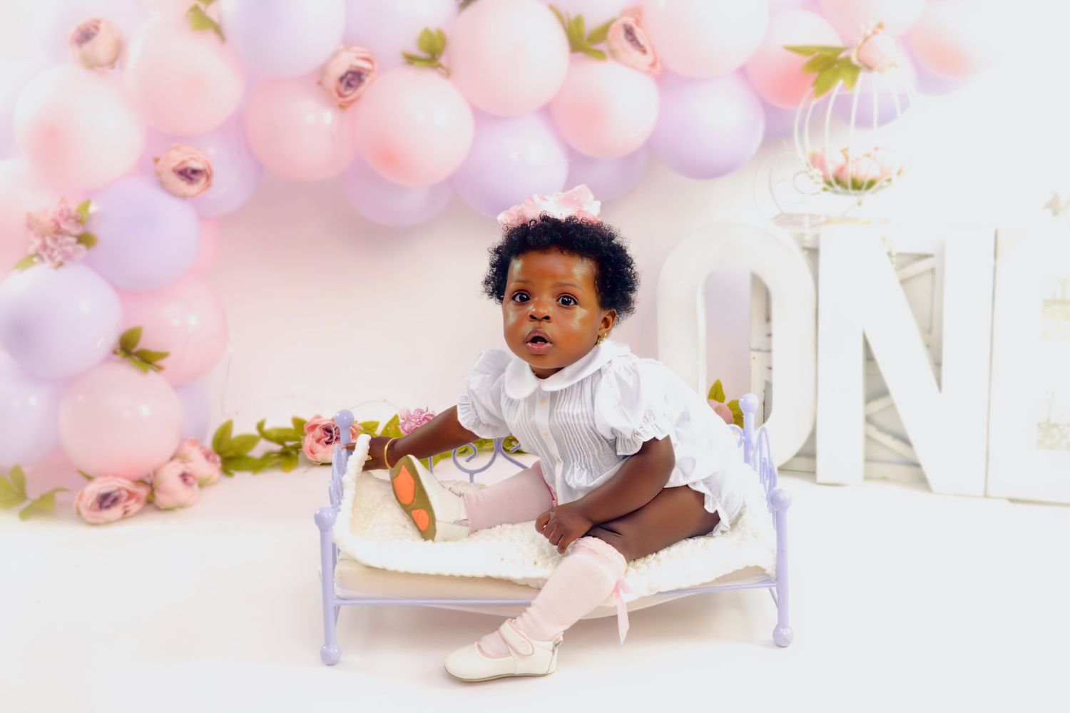 Luxurious pink and white balloon installation with floral elements for photography.