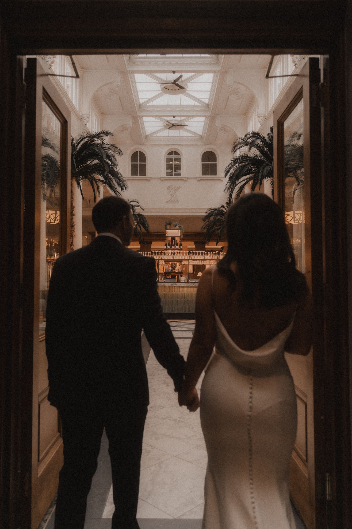 A series of wedding photos showing a couple walking down an elegant hallway in sepia tones.