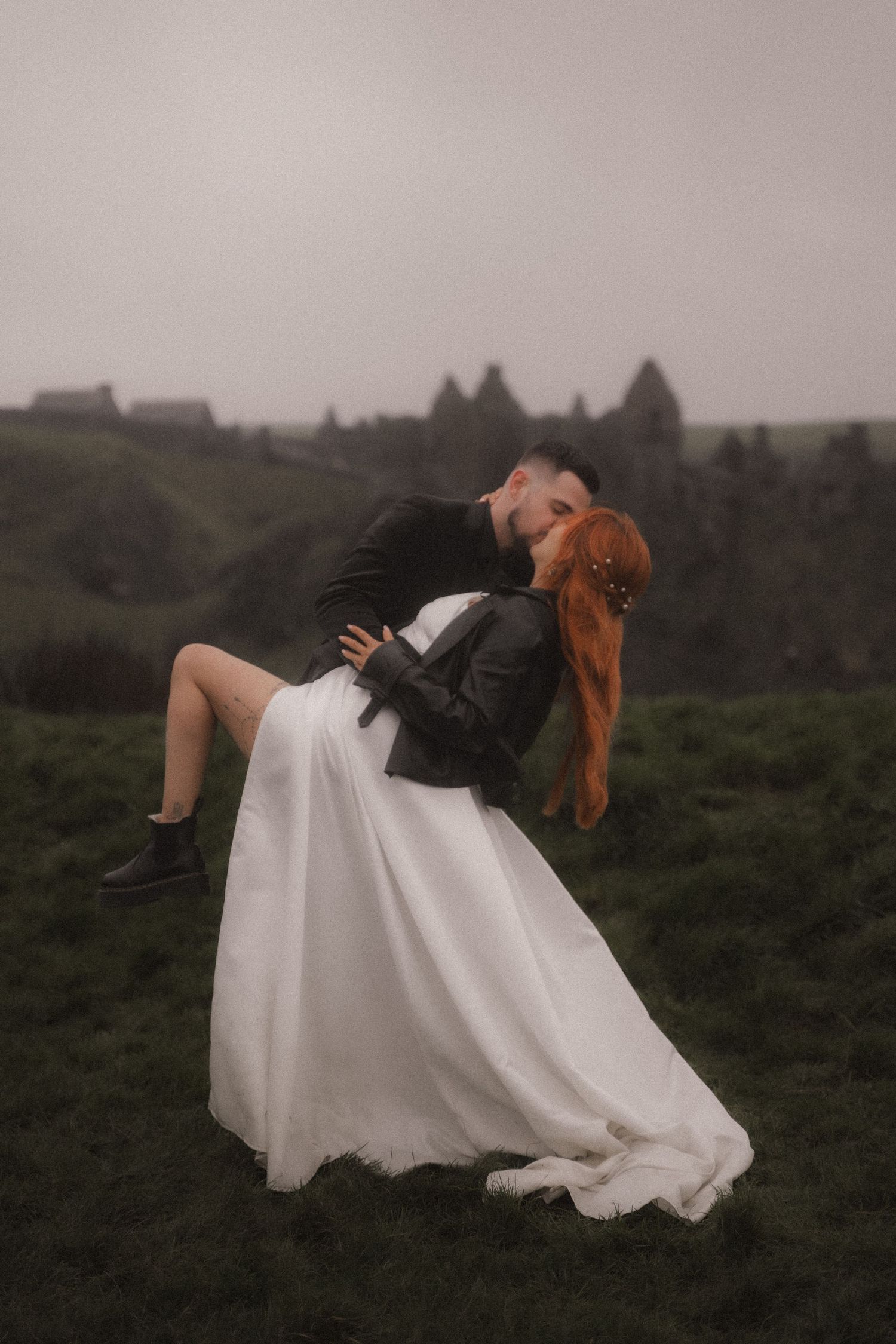 A romantic wedding pose against a moody mountainous backdrop.