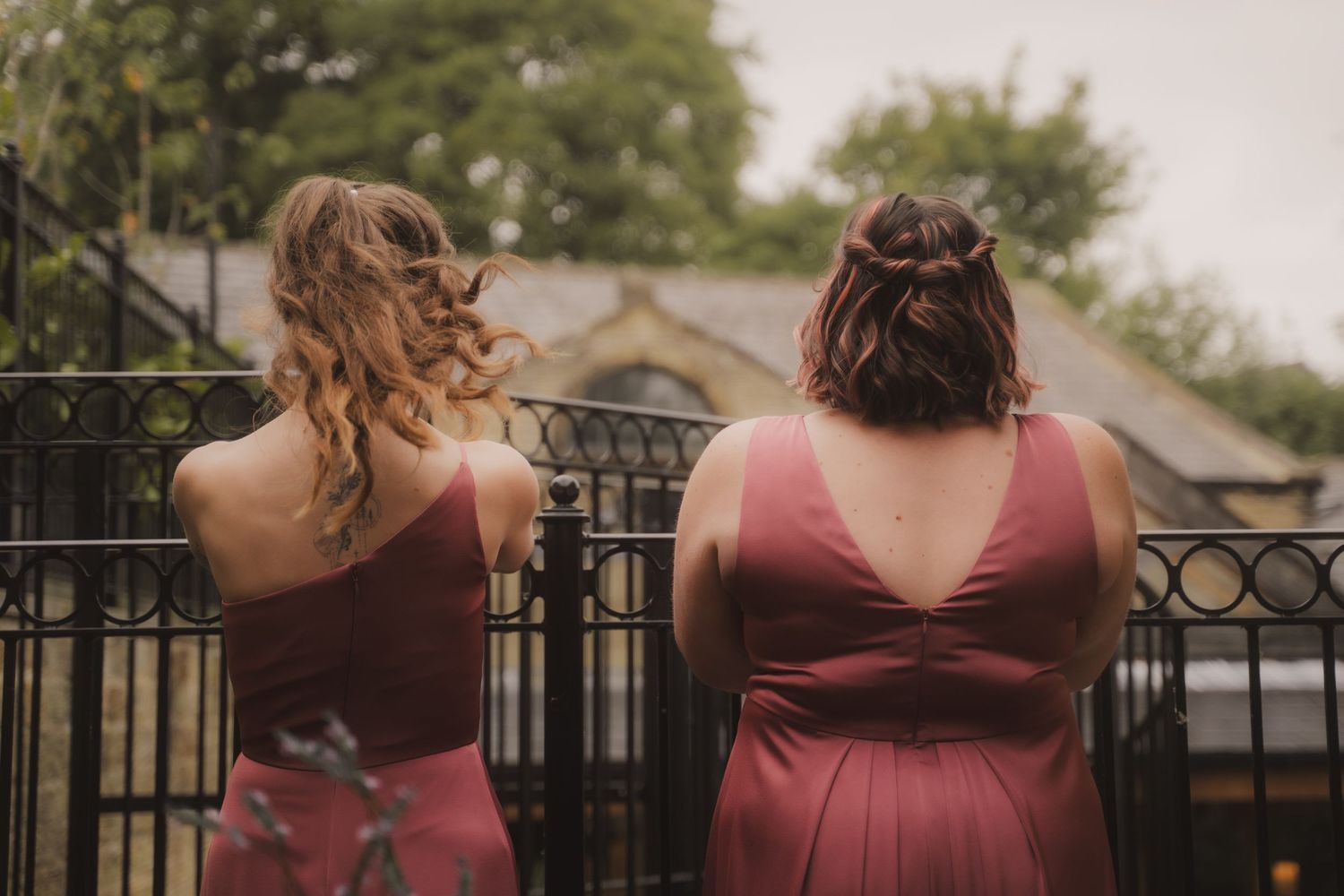 A series of wedding party photos showing people in burgundy dresses standing against an iron railing outdoors.