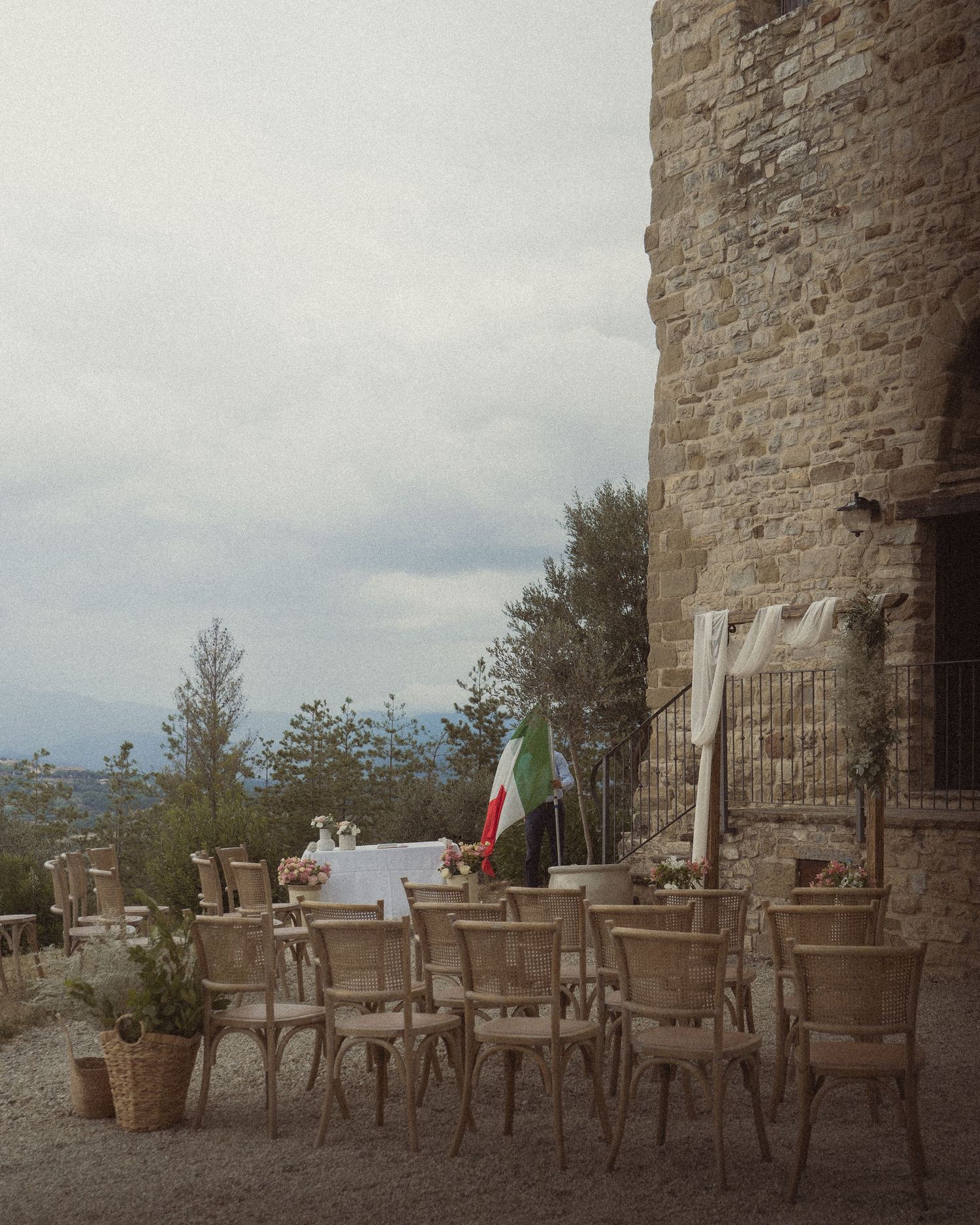 An outdoor dining area with rustic chairs set up against a stone wall with mountain views.