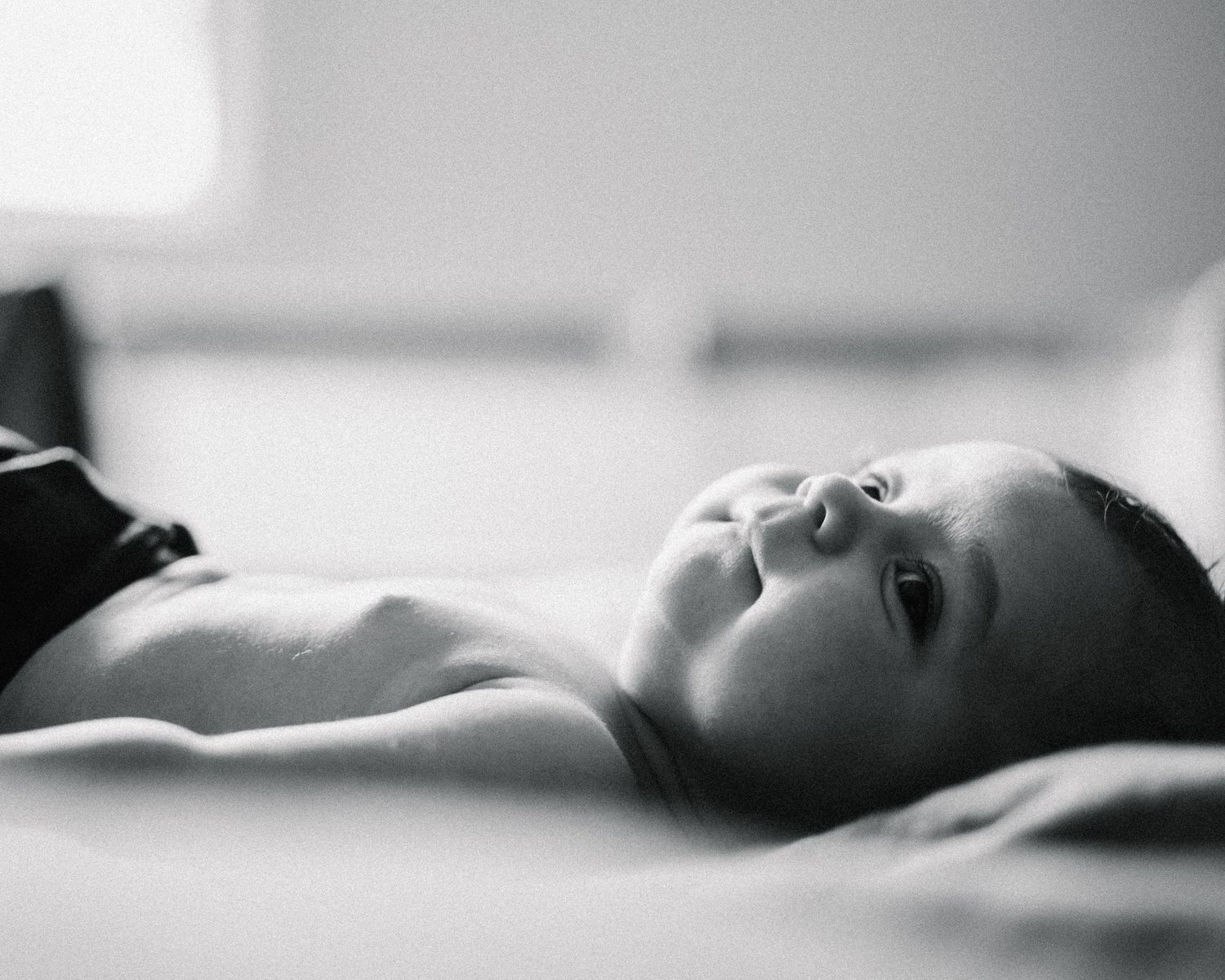 Artistic black and white portrait series showing someone reclining in soft, dramatic lighting.