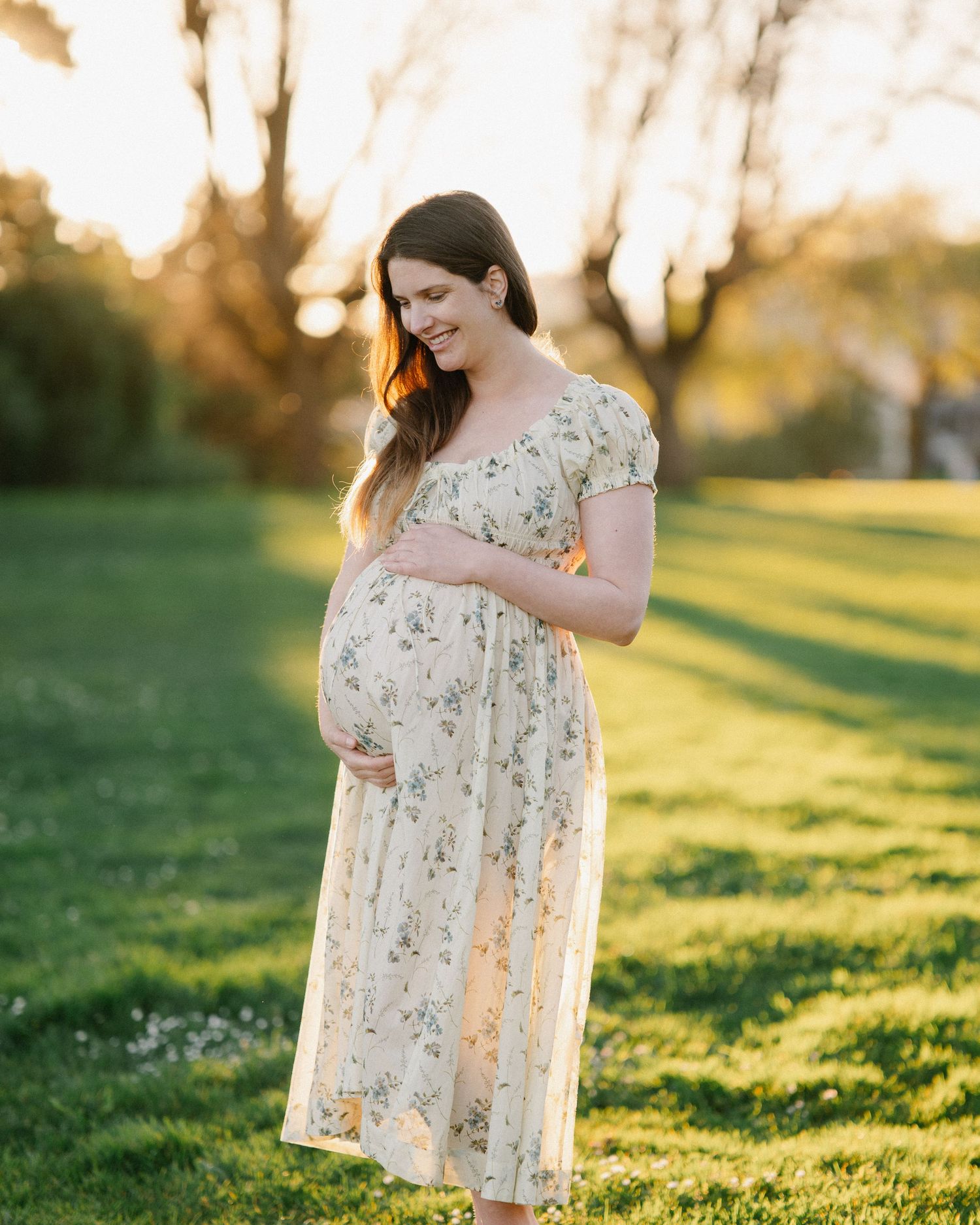 A floral dress catches golden sunlight in a grassy field during sunset, creating a dreamy springtime scene.