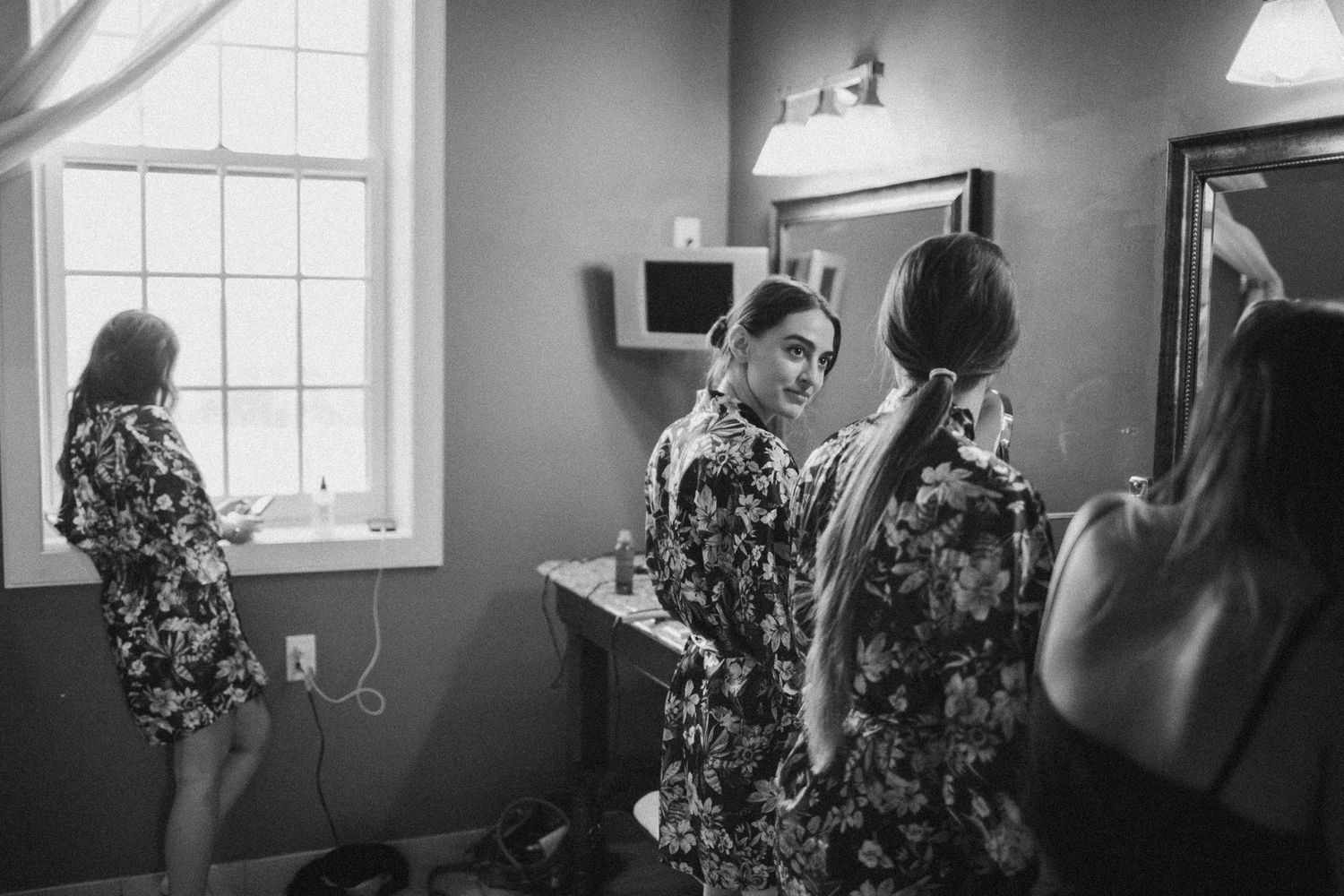 Black and white photo of a bridal preparation scene with window light.
