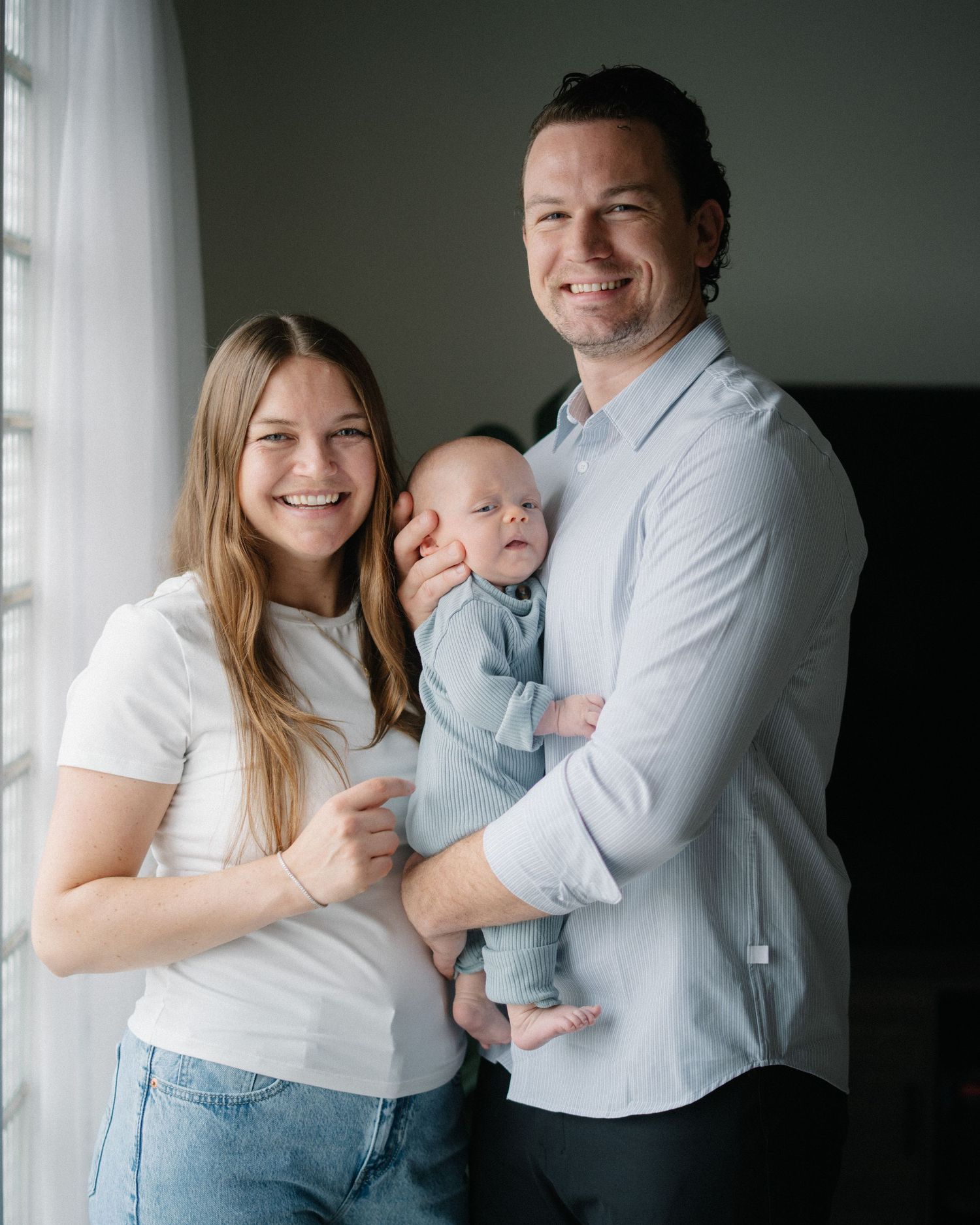 A family poses together in a series of candid moments against a neutral background, wearing white and blue clothing.