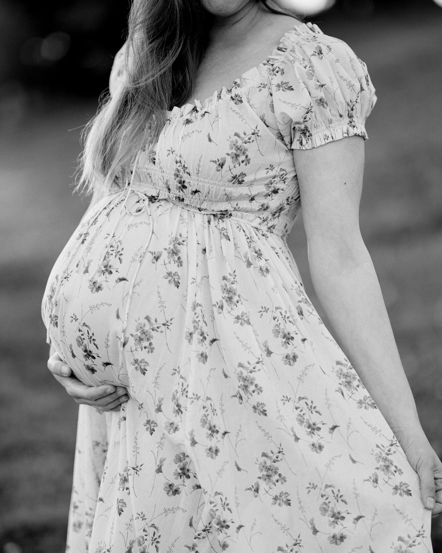 A black and white capture shows the delicate details of a floral dress in soft natural light.