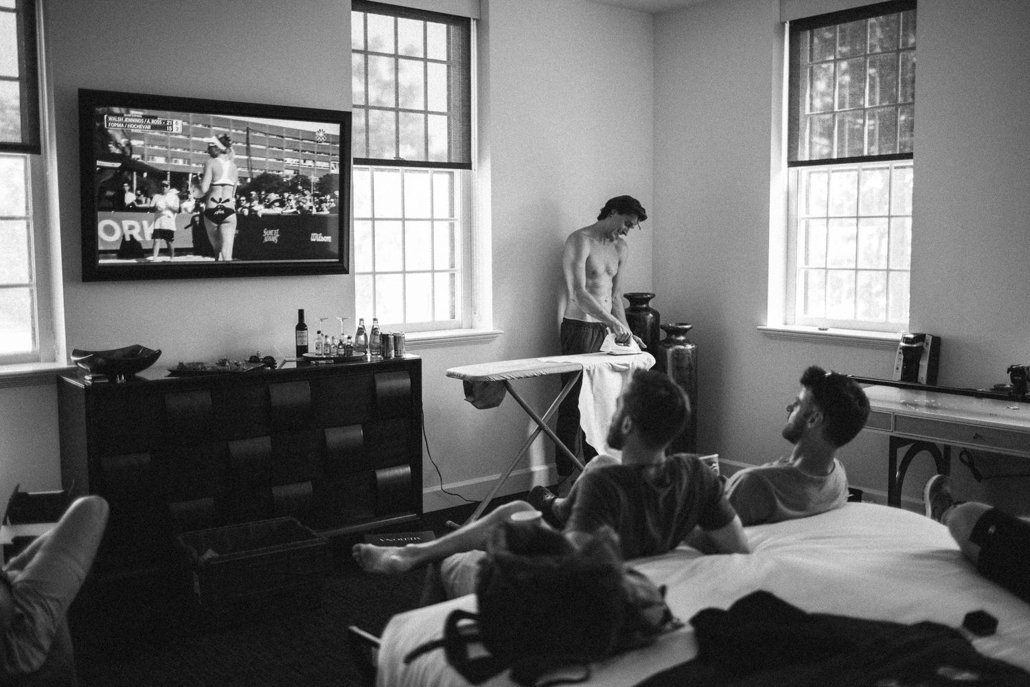 Black and white photo of a room with multiple windows and furniture in a minimalist setting.