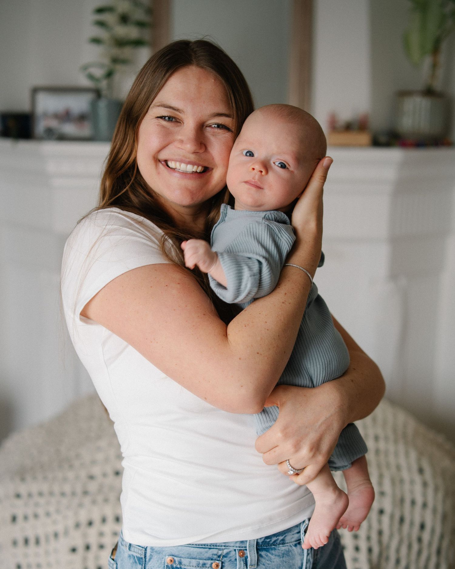 A tender moment captured in a bright indoor setting as a baby is held close in a loving embrace.