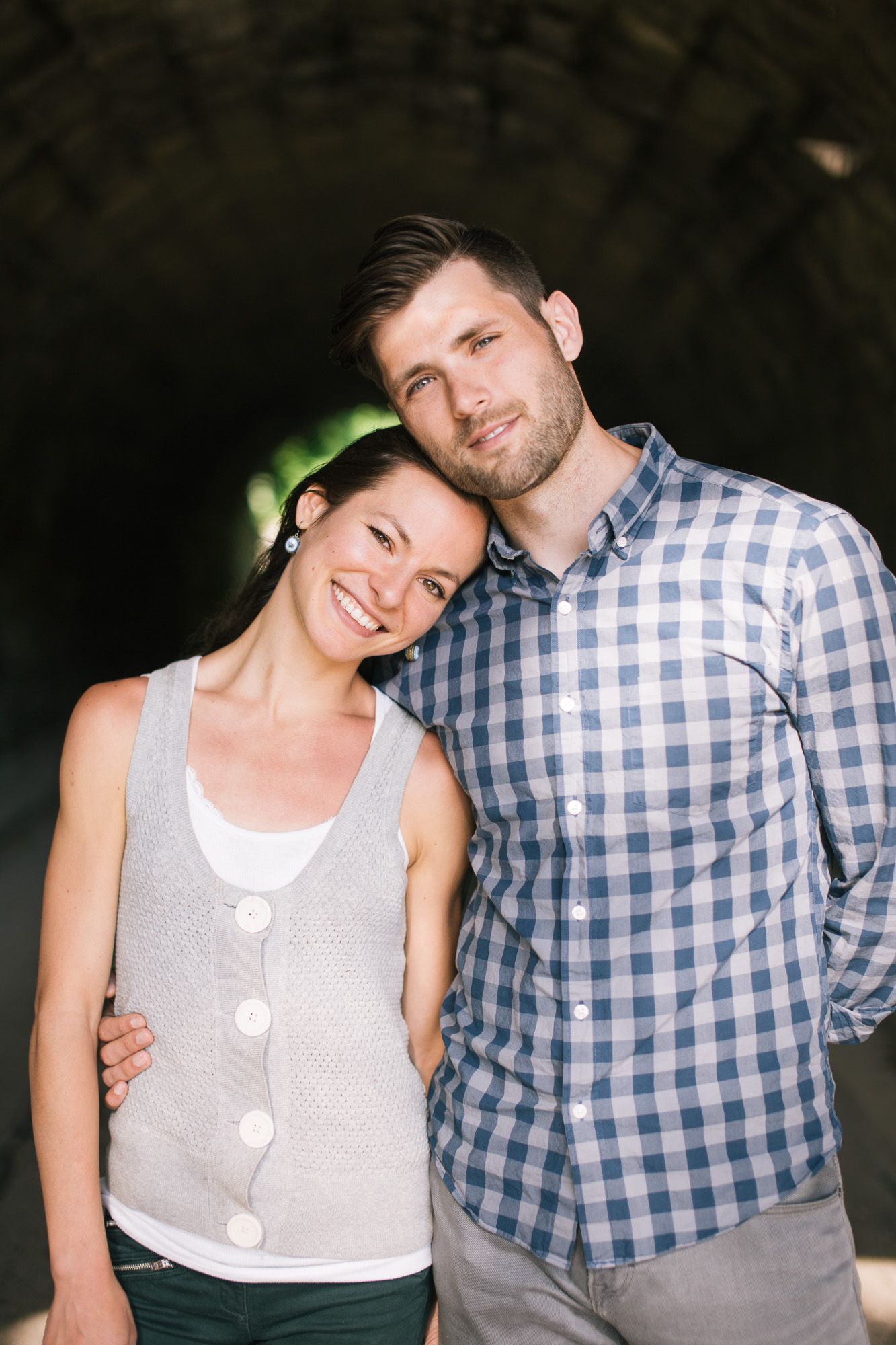 A couple poses playfully in a series of black and white photos wearing casual attire of plaid and white tops.