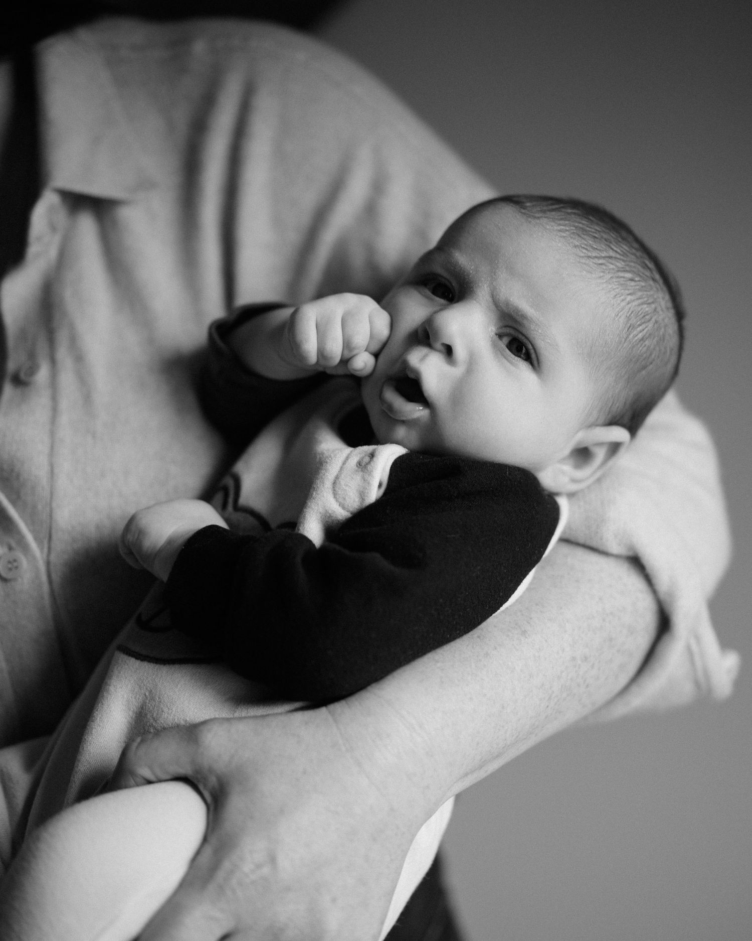 Black and white sequence showing a baby lying down and yawning in soft natural light.