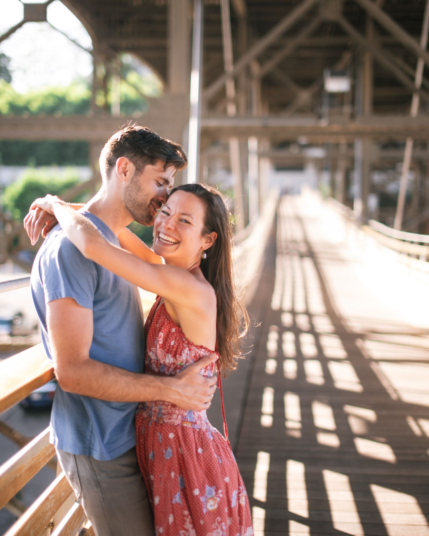 A couple dancing together in a rustic barn with dramatic shadows and sunlight streaming through wooden beams.