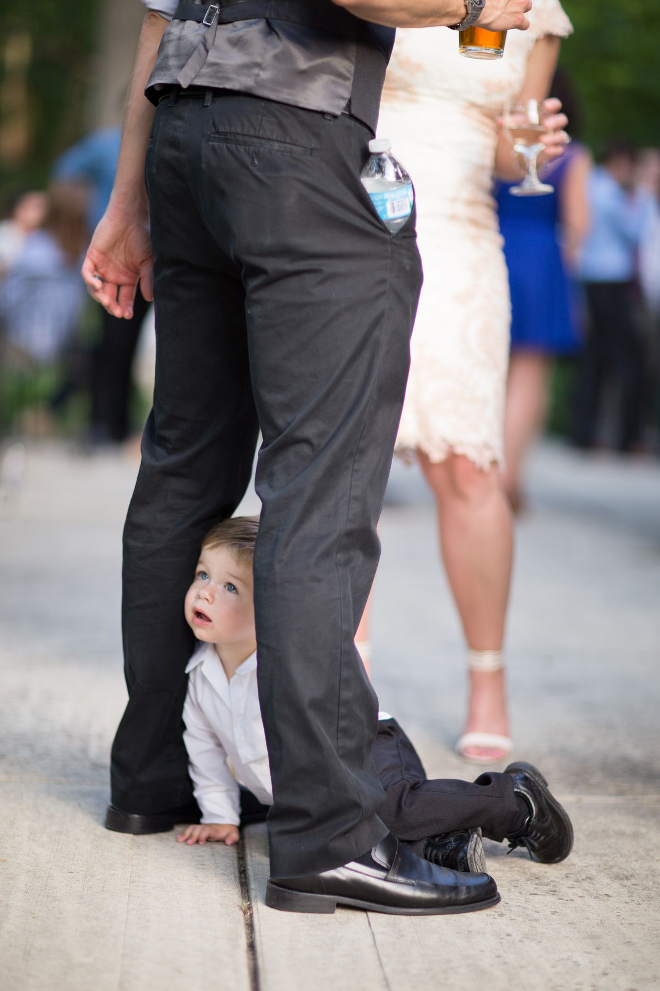 Close-up view of formal dress shoes and feet on a stone pathway at a wedding celebration.