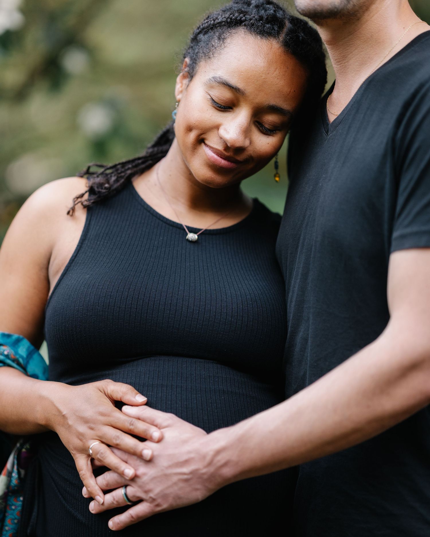 Romantic pregnancy photoshoot series showing tender moments between couple in black clothing outdoors.