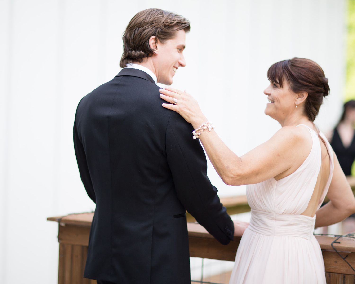 A couple in formal wedding attire dance together in a romantic moment captured in black and white.