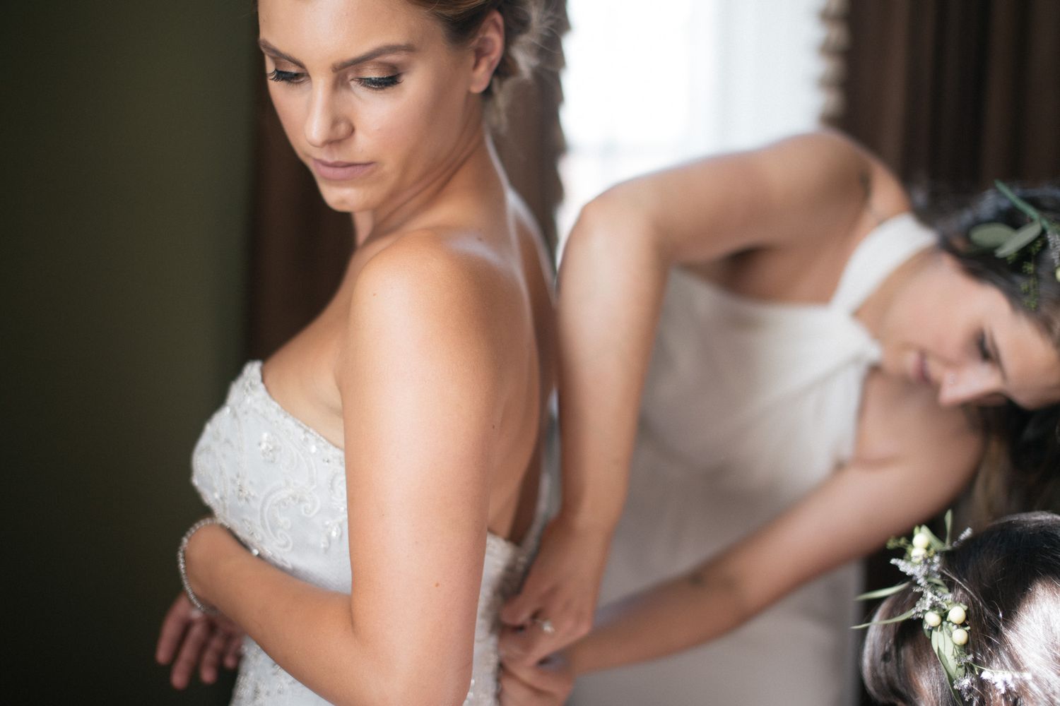 Close-up view of wedding dress details being adjusted in soft lighting.